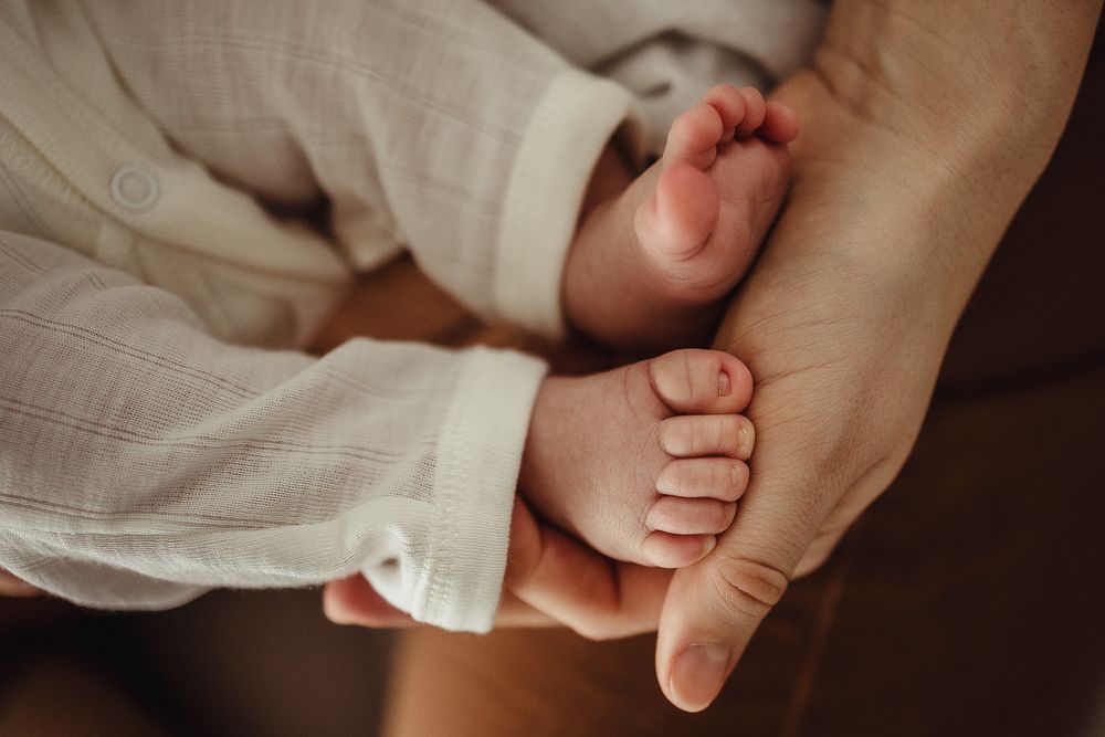 A series of close-up photos showing tiny baby feet being gently held by adult hands.