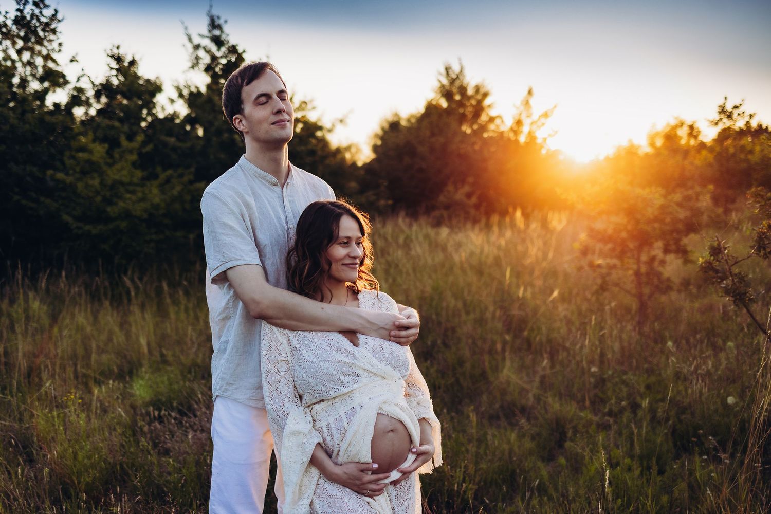 Golden hour maternity photos captured in a natural outdoor setting with warm sunlight.