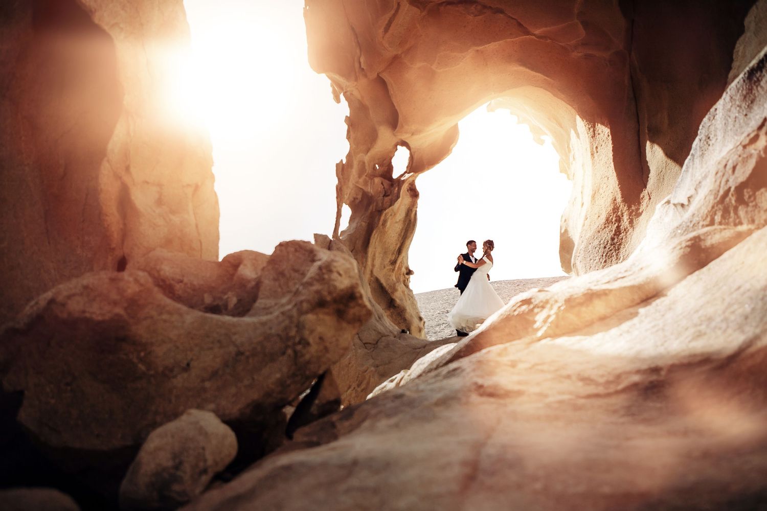Wedding couple dancing under the natural stone arch at Arco de las Peñitas, Fuerteventura - Photography by photoFuerte