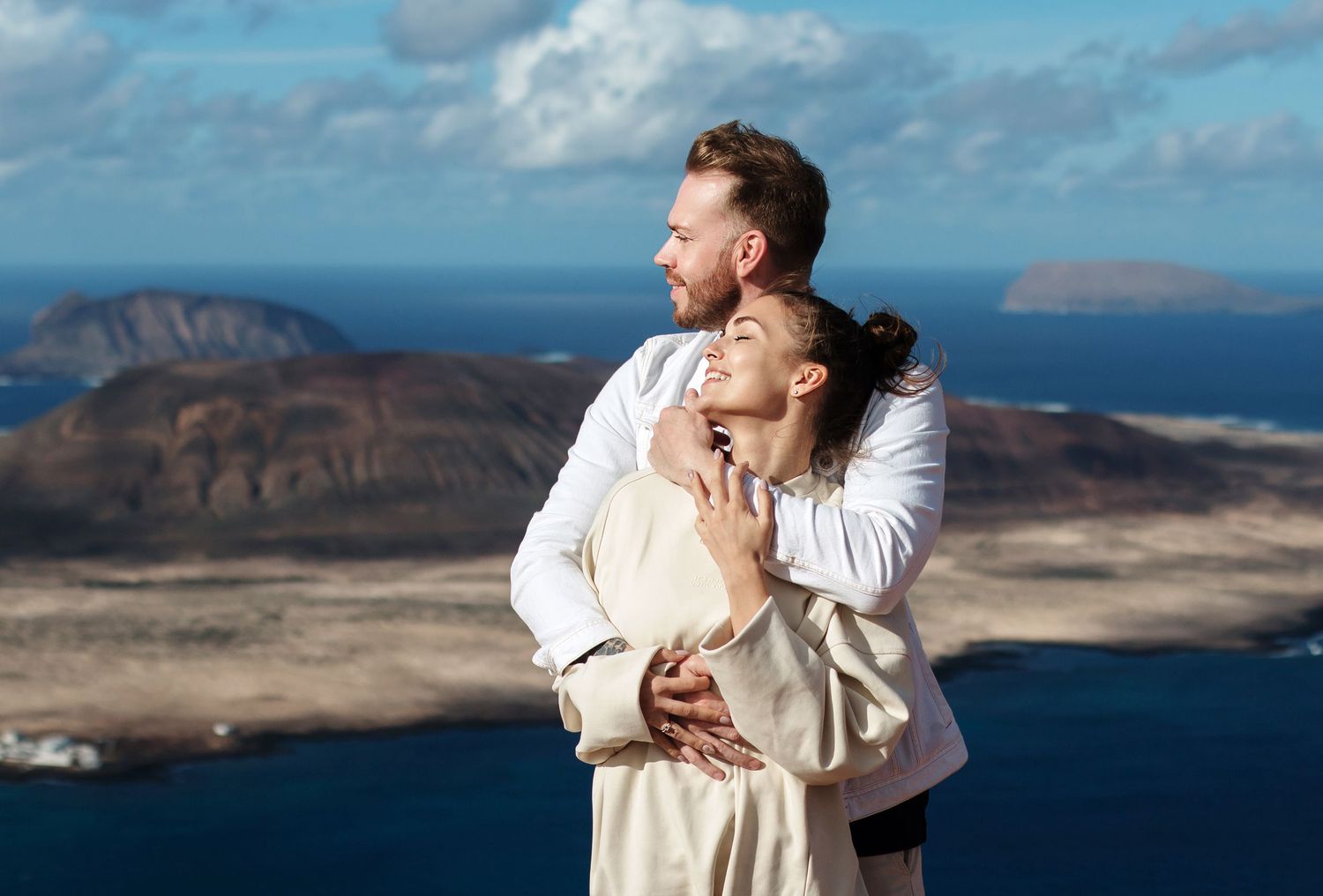 Couple embracing with the view of La Graciosa island in the background - Wedding photographer in Lanzarote