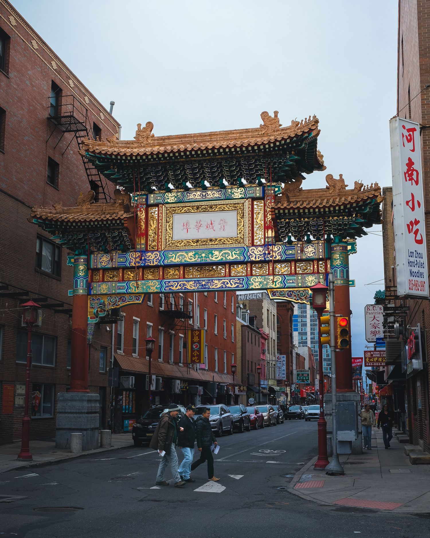 L'arche traditionnelle du quartier chinois de Philadelphie surplombant une rue animée. Photographie de patrimoine urbain et de voyage.