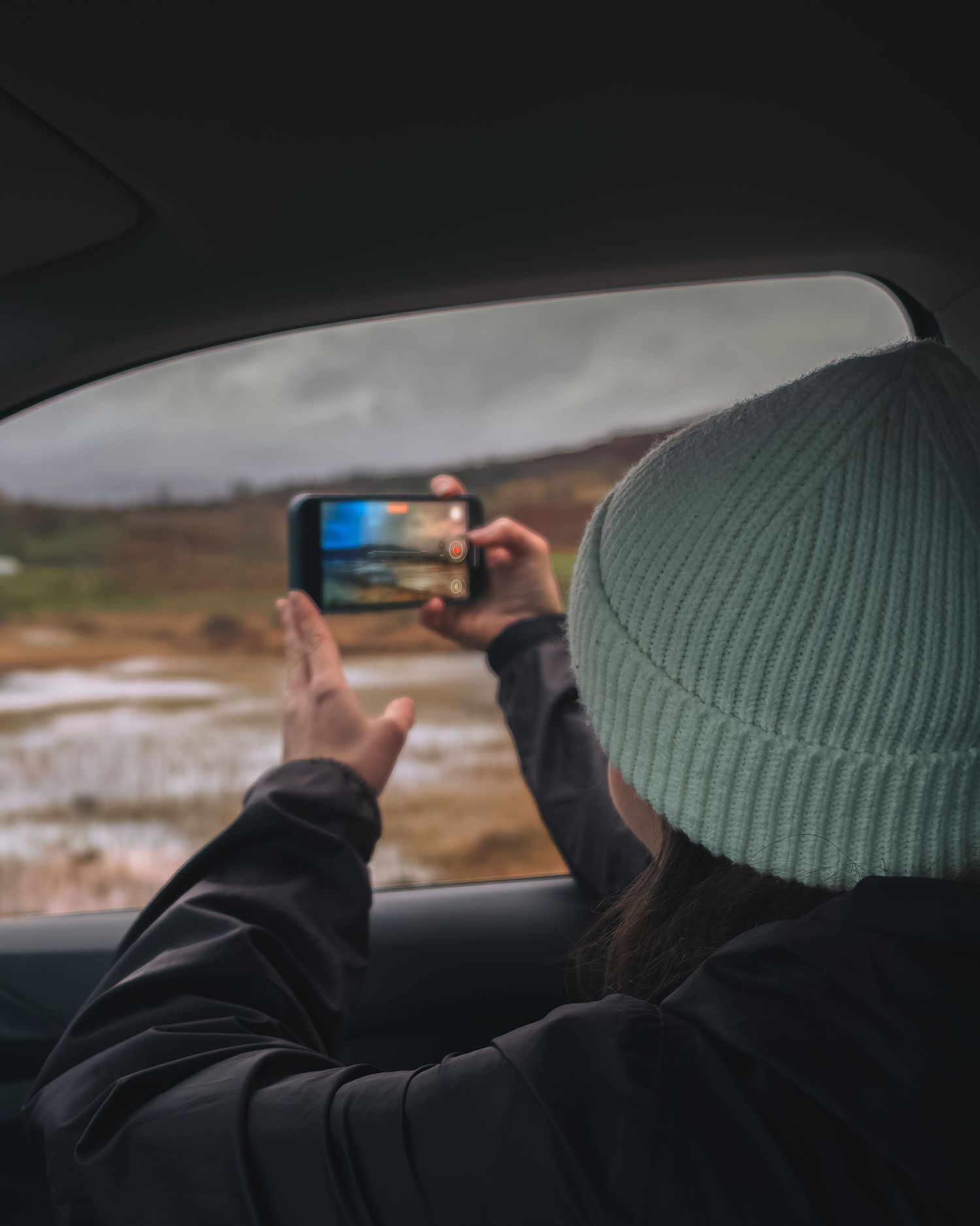 Voyageur en bonnet capturant la beauté sauvage des Highlands, concept de voyage itinérant et de photographie mobile.