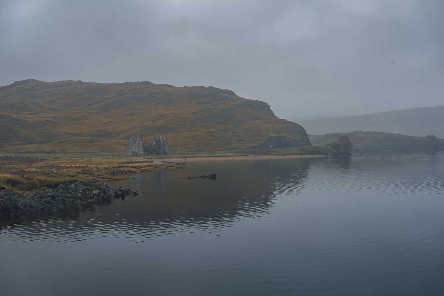 Ruines d'un château en bord de loch sous la brume en Écosse. Atmosphère mélancolique et paysage sauvage des Highlands. Photo de voyage.
