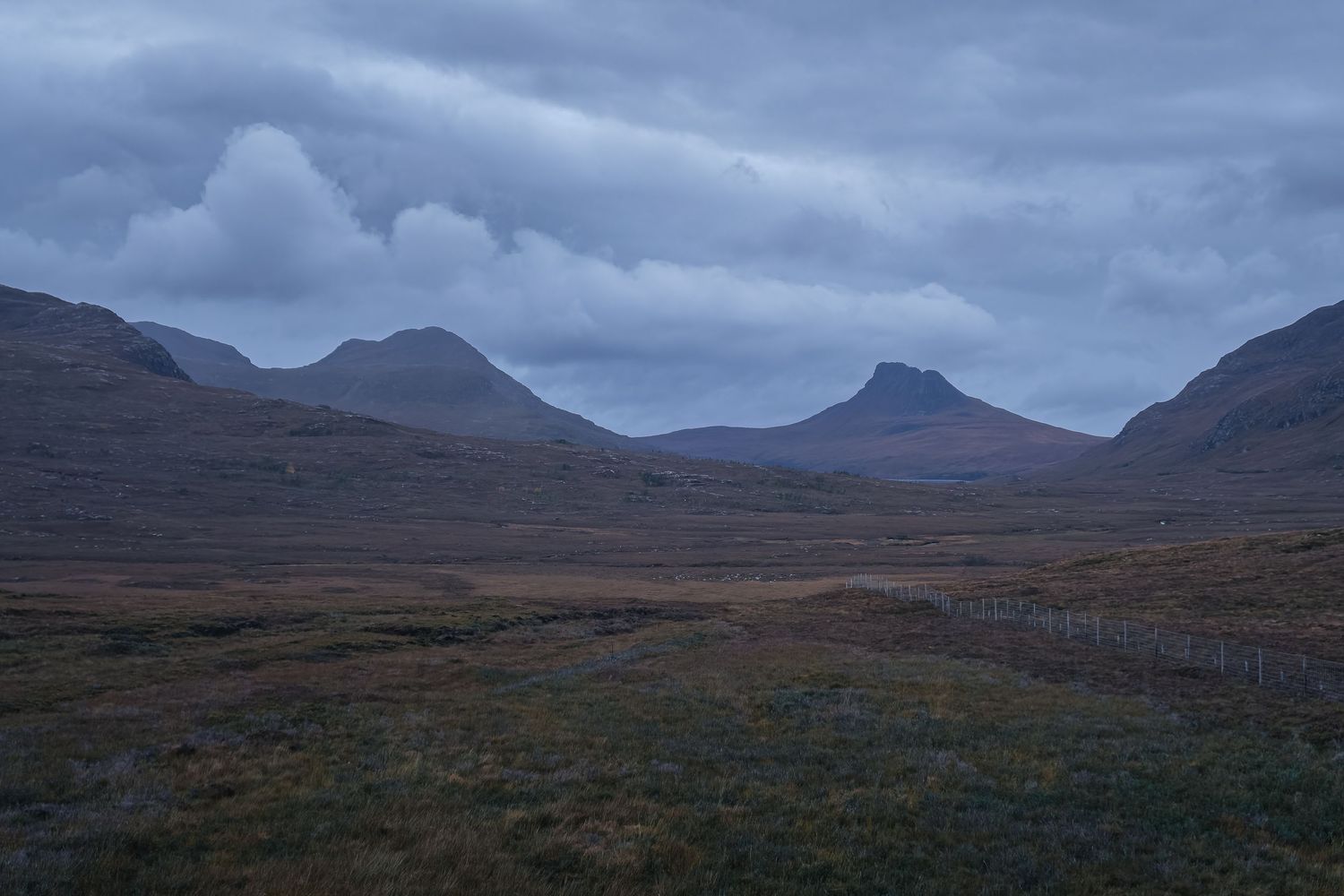 Panorama de lande et montagnes écossaises sous un ciel nuageux. Paysage sauvage des Highlands pour randonnée et tourisme d'aventure.