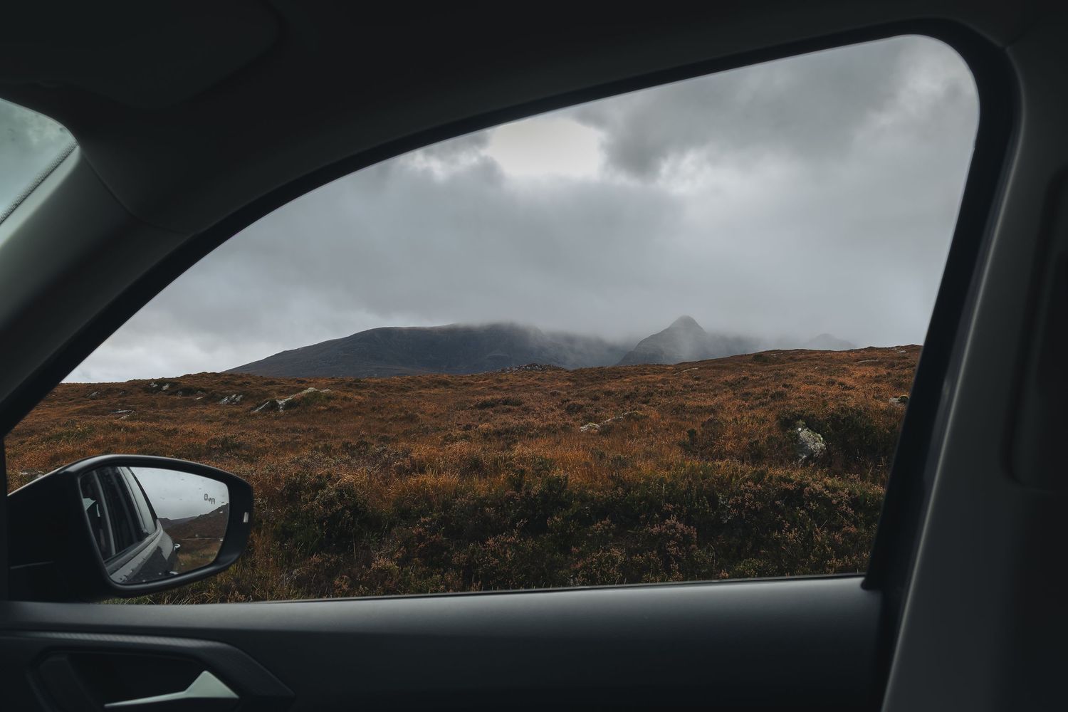 Vue panoramique sur les montagnes écossaises à travers la vitre d'une voiture, paysages des Highlands en plein road trip.