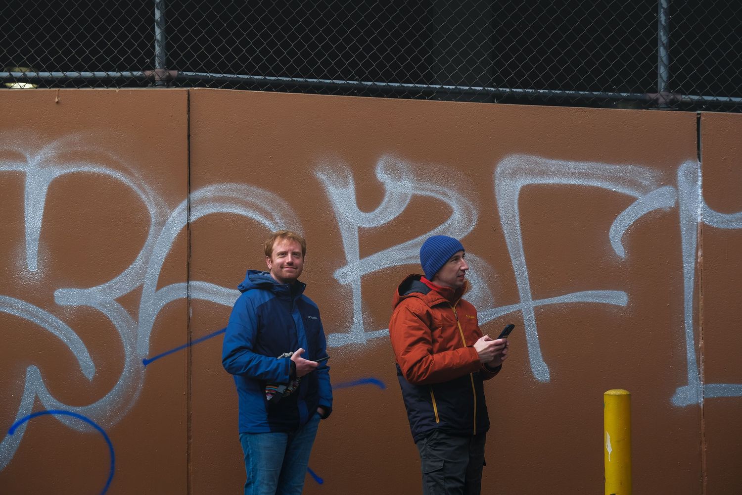 Photographie de rue à Philadelphie : deux hommes devant un mur de graffitis. Reportage urbain par un photographe de tourisme outdoor.