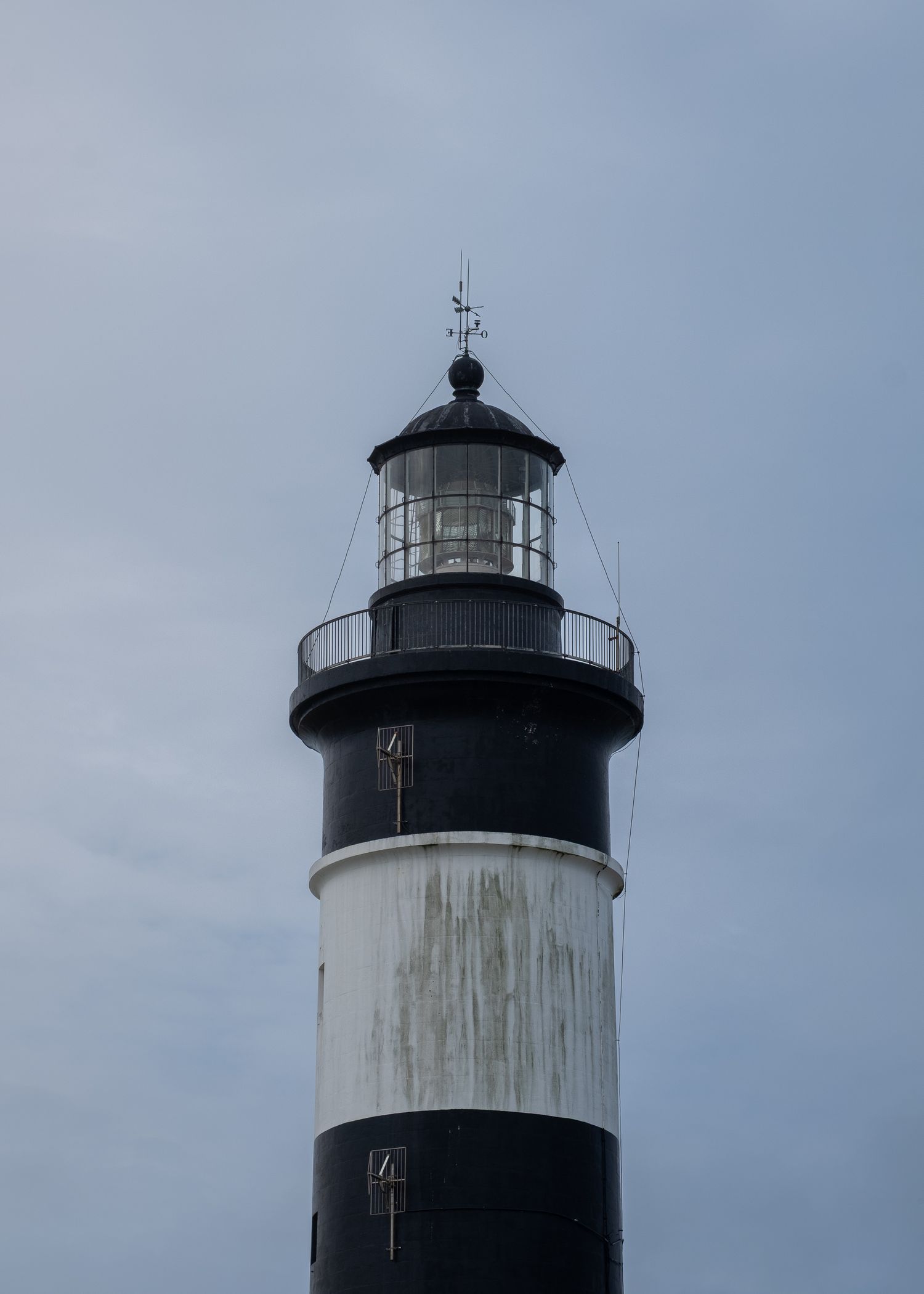 Partie supérieure du phare de l'Île d'Oléron, lanterne noire et fût blanc sous ciel gris. Point d'intérêt tourisme.