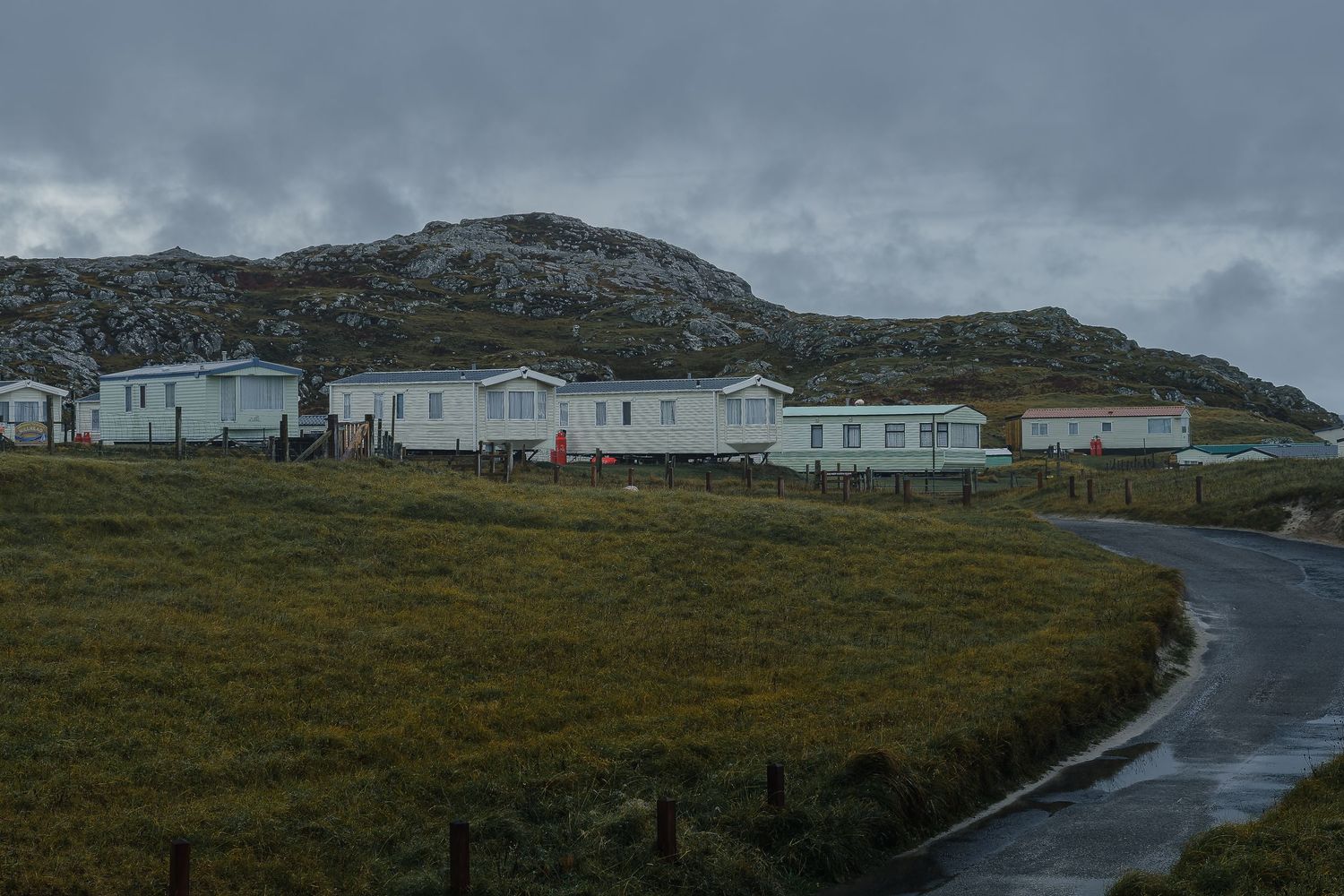 Mobil-homes blancs alignés à Scourie face aux collines rocheuses. Photographe tourisme et activité plein air pour hébergement outdoor.