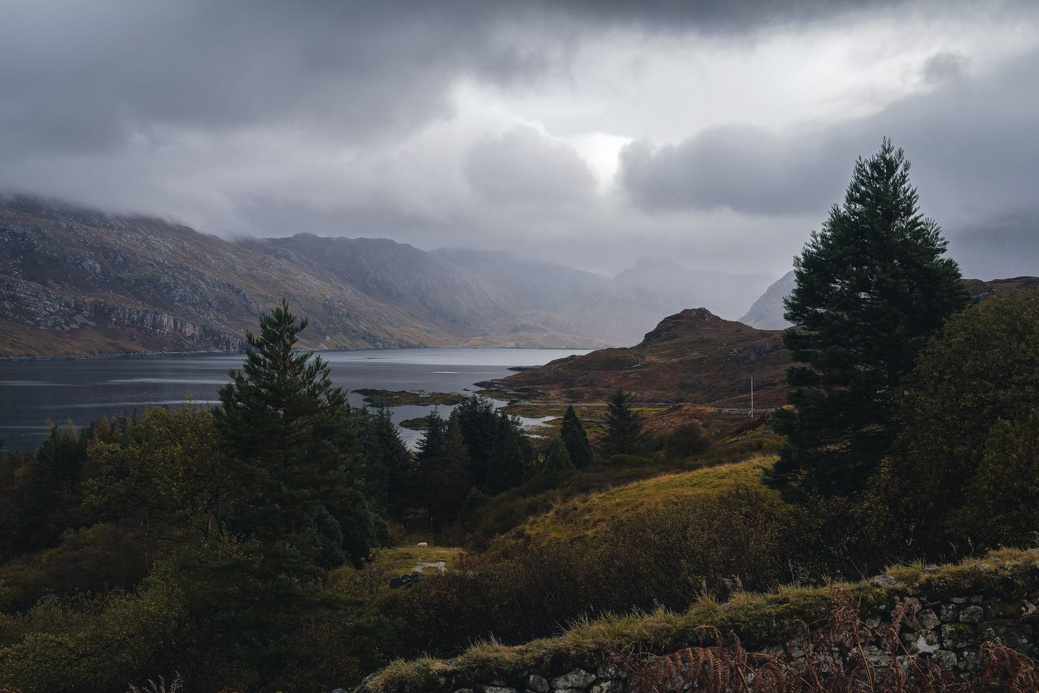 Vue panoramique d'un loch en Écosse sous un ciel orageux. Photographie outdoor Highlands pour tourisme d'aventure et randonnée sauvage.