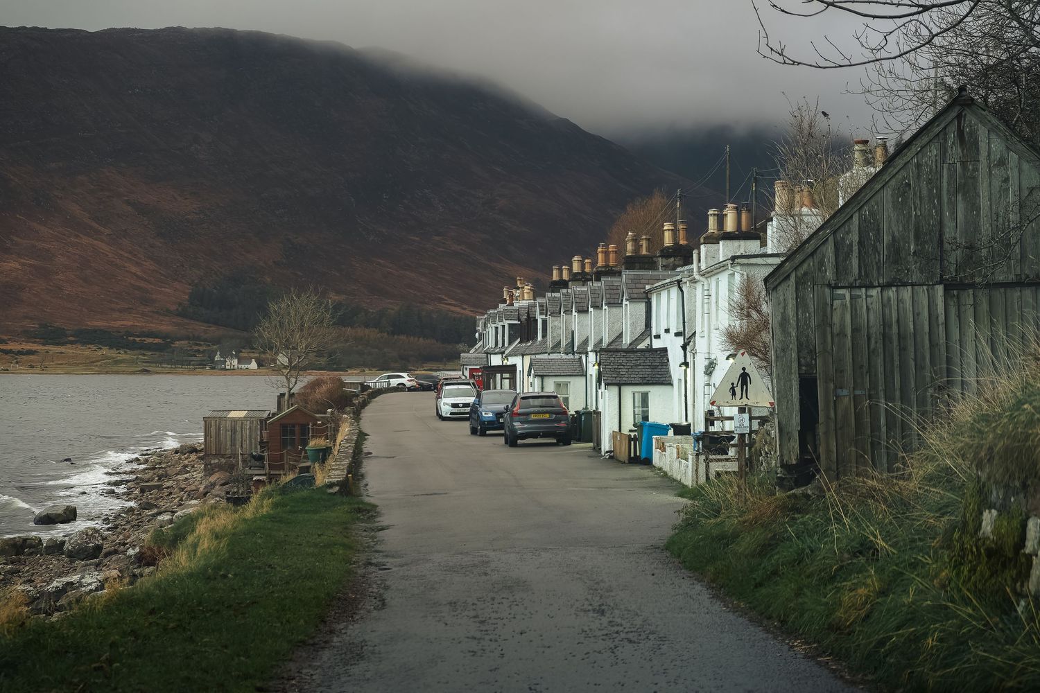 Alignement de cottages blancs traditionnels sur la côte d'Applecross en Écosse, ruelle typique des Highlands au bord de l'eau.