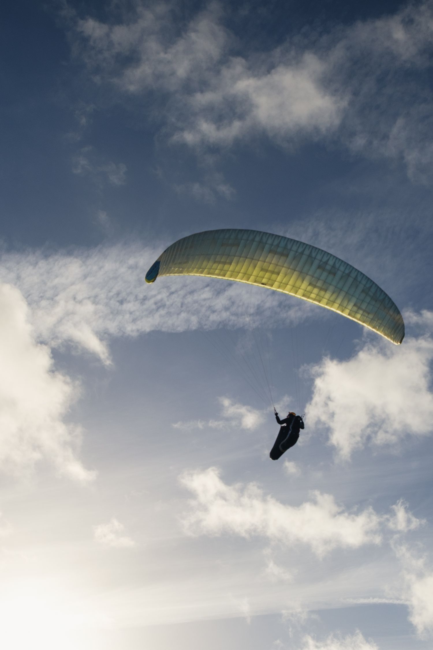 Parapente en plein vol sous un ciel nuageux contrasté. Photographie outdoor capturant la liberté et les activités de plein air.