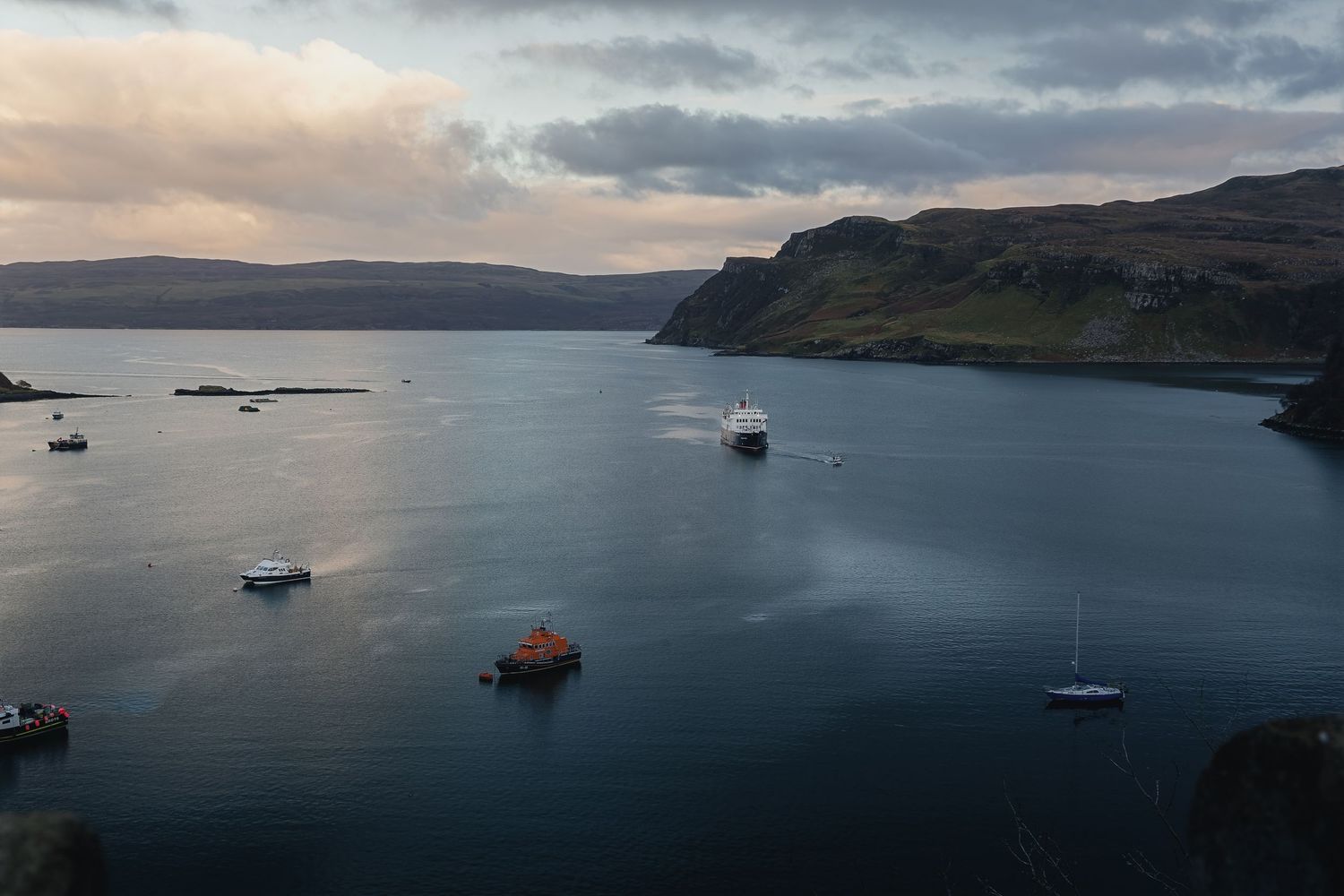 Bateaux au mouillage dans la baie de Portree sur l'île de Skye, sous un ciel de fin de journée. Photo de destination et paysage écossais.