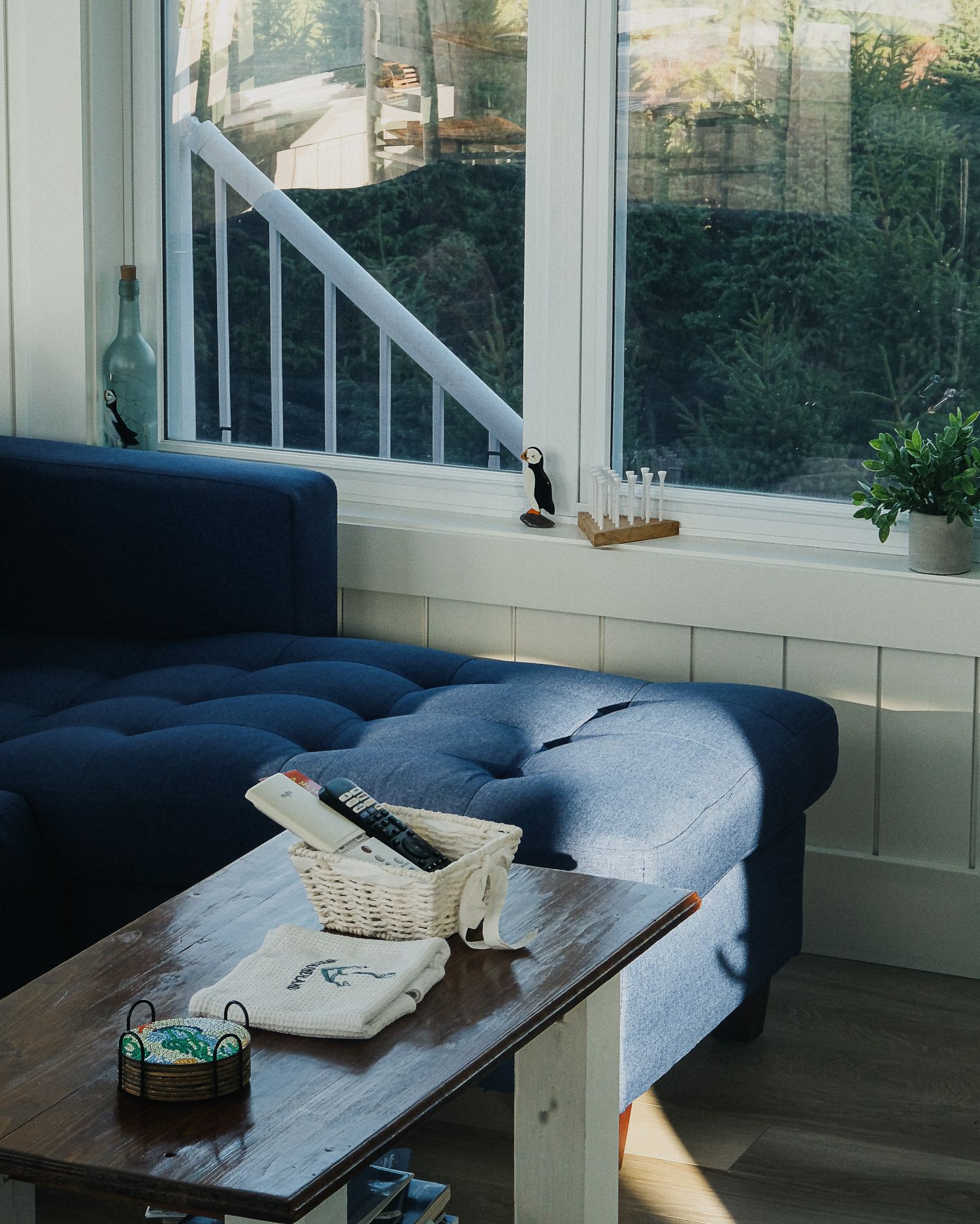 Détail de la décoration intérieure d'un hébergement à Dildo : canapé bleu capitonné, table en bois naturel et accessoires de style bord de m
