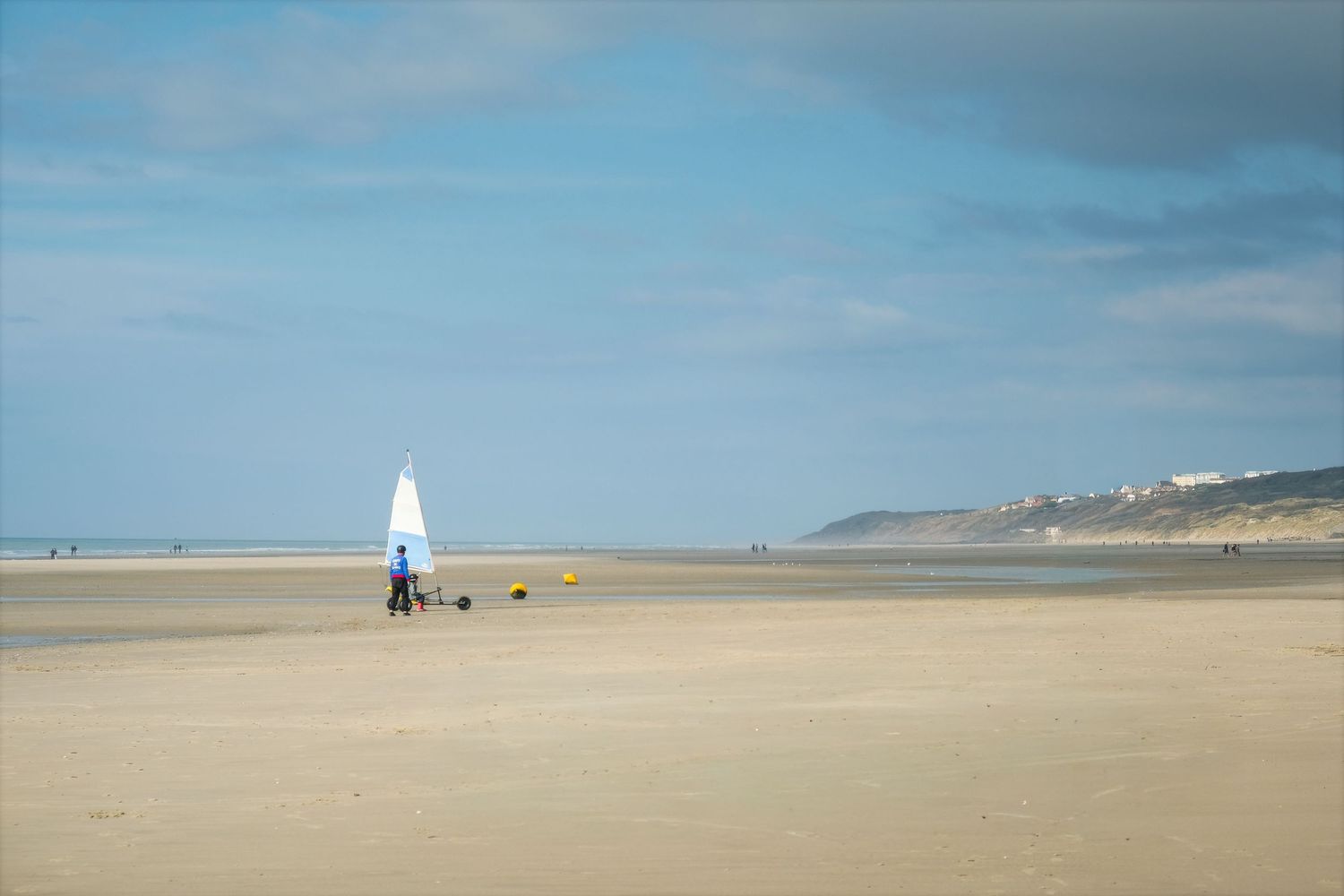 Char à voile solitaire sur l'immense étendue de sable d'Équihen-Plage, sous un ciel changeant. Photographie outdoor et sport de plein air.