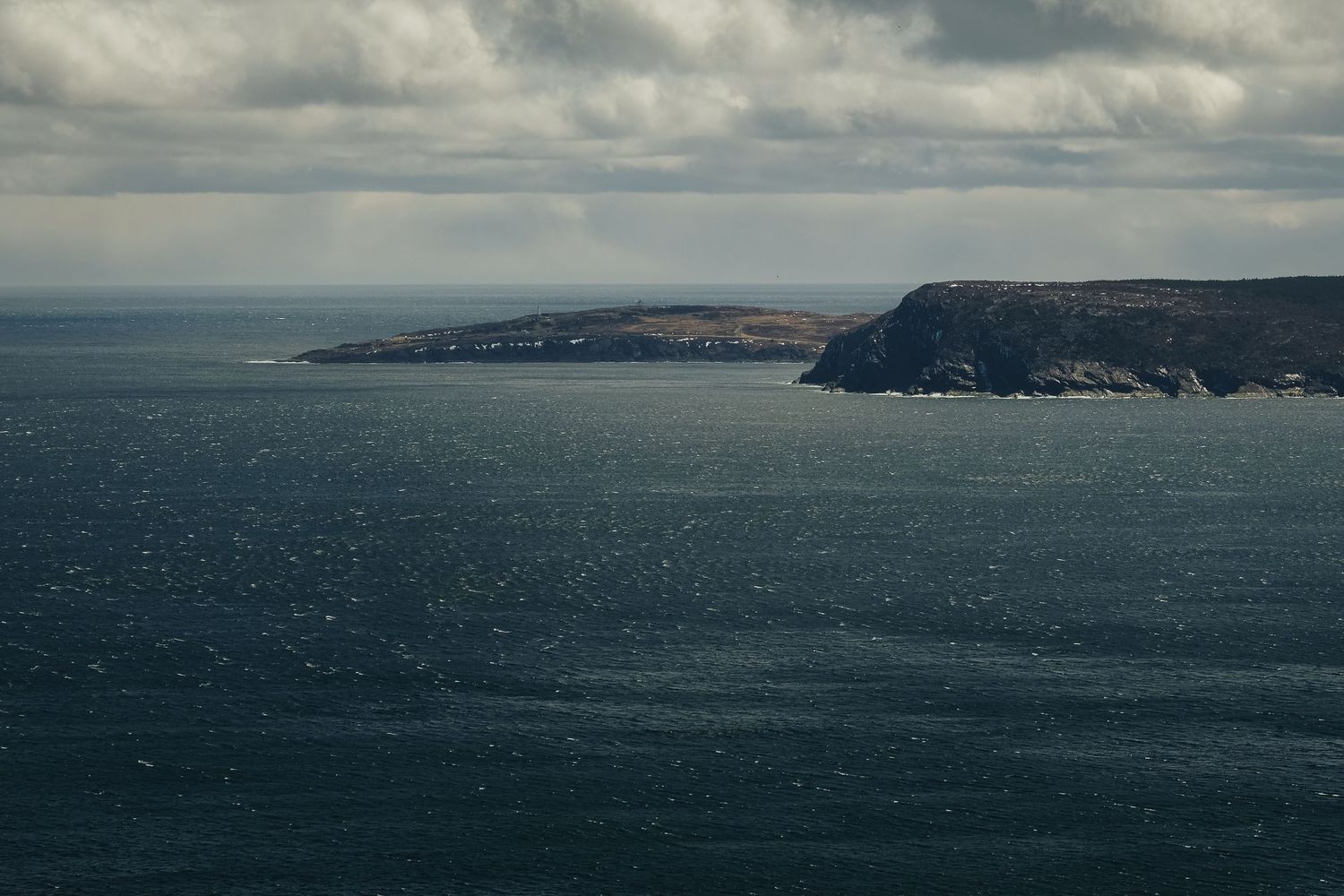Falaises rocheuses escarpées et mer agitée près du phare de Cap Spear, Terre-Neuve.