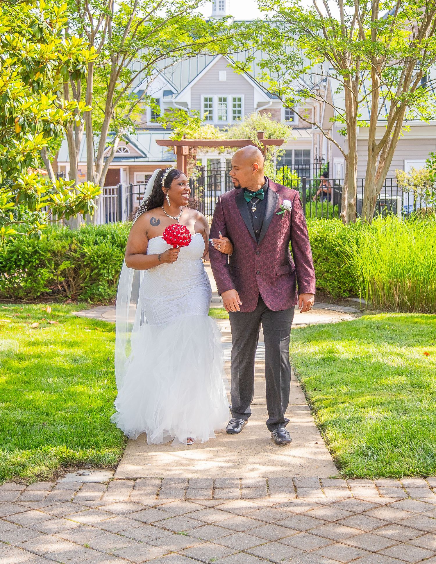 Wedding processional on stone pathway through landscaped garden.