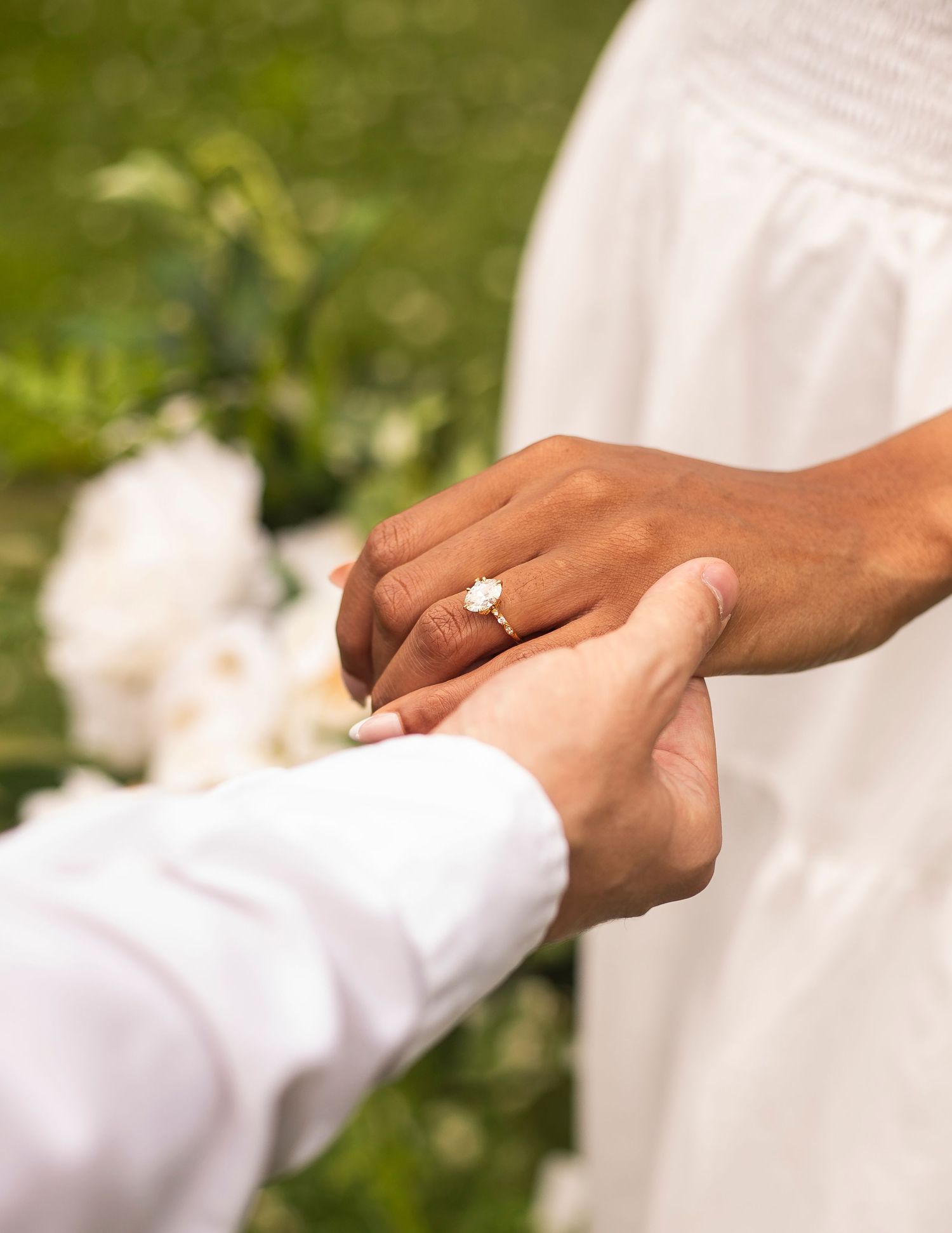 Close-up of hands with engagement ring during romantic outdoor proposal.