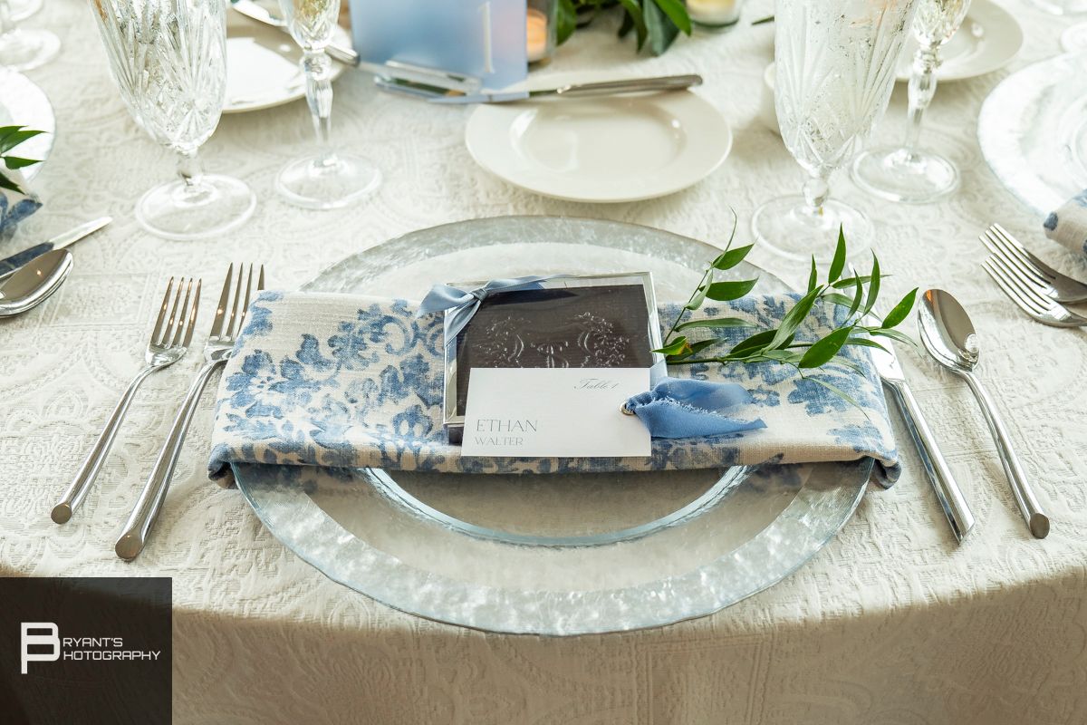 Elegant table setting with white linens, fine china, and delicate floral arrangements.