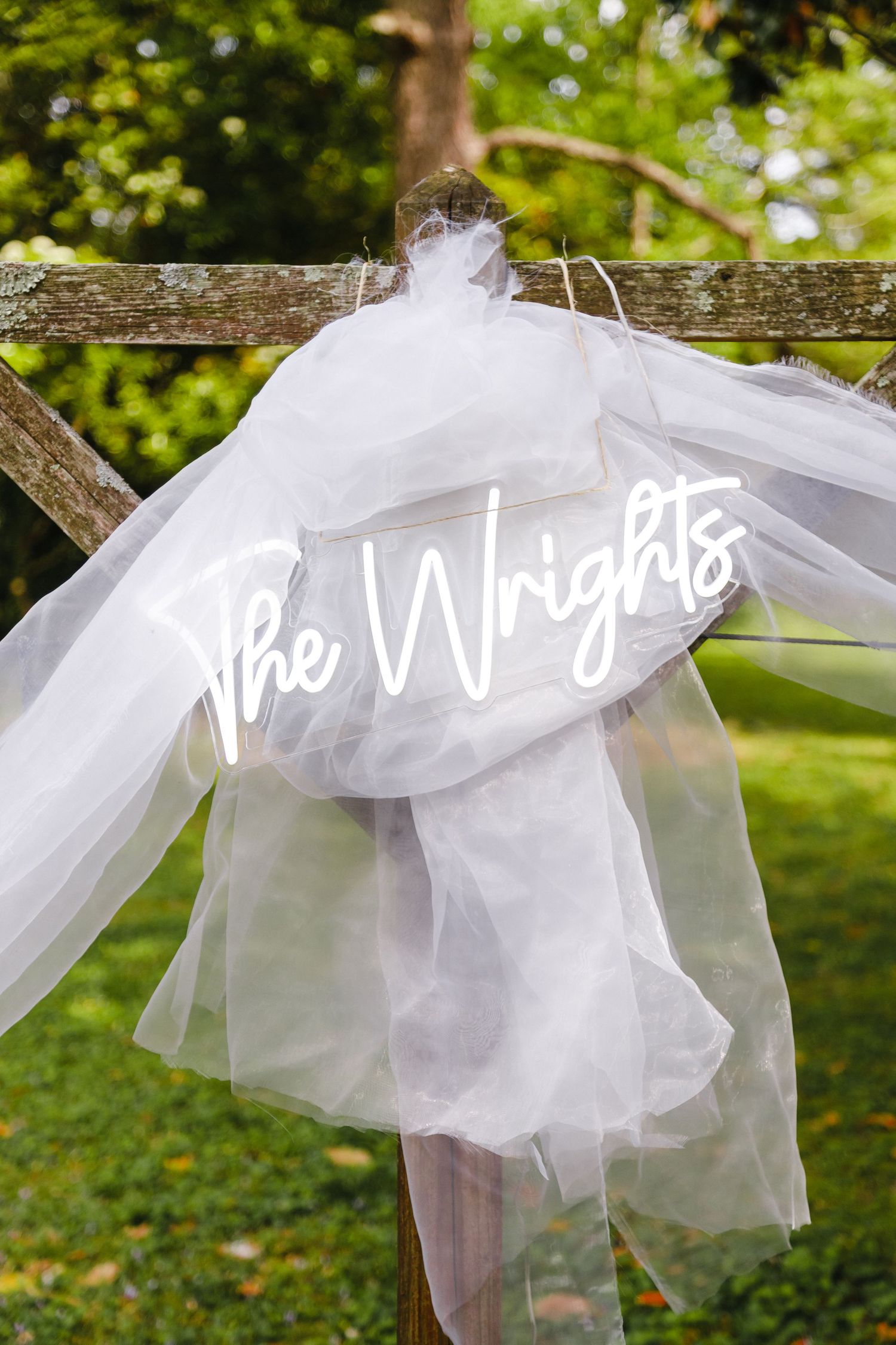 White tulle decorations hanging on a line outdoors with green foliage in background.
