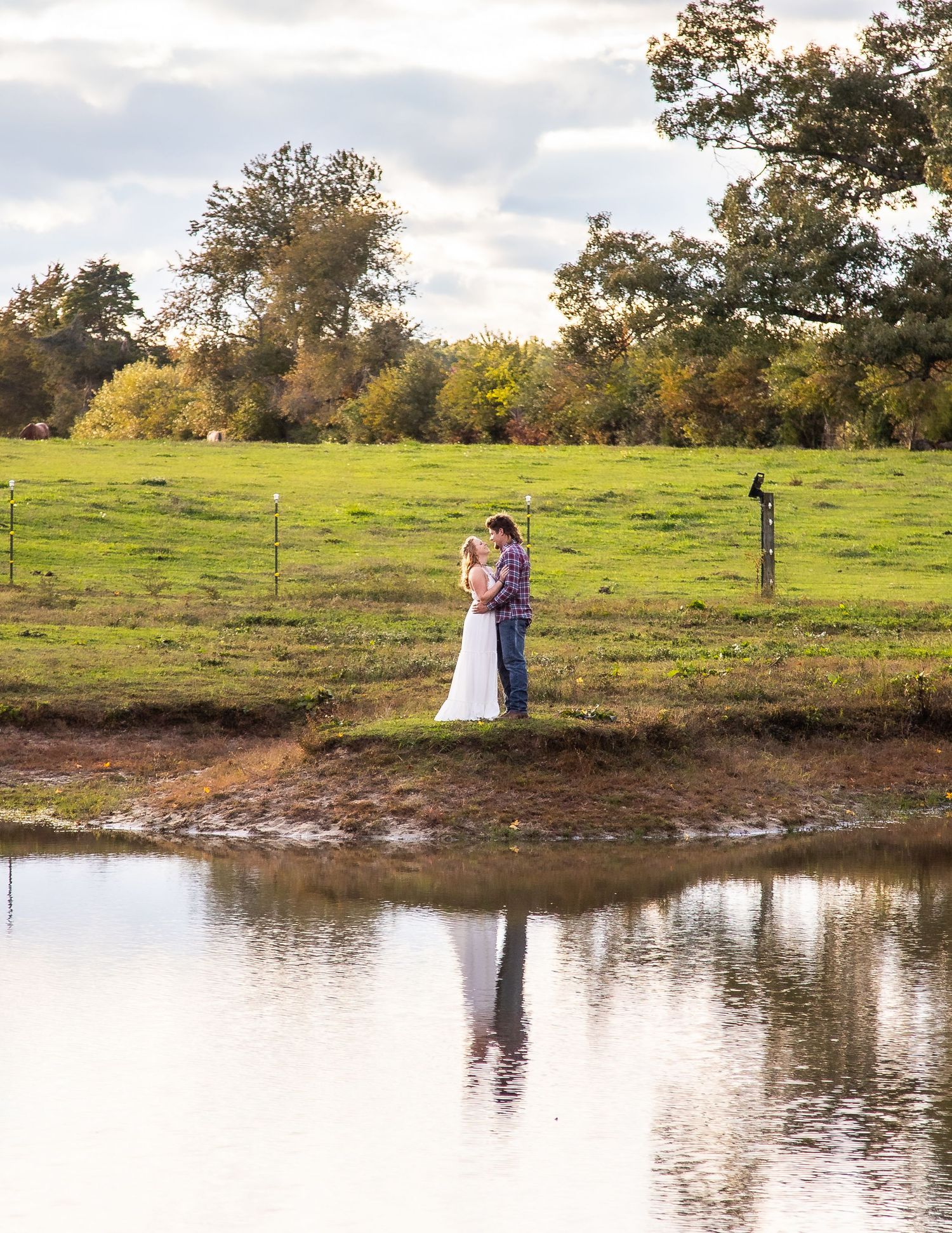 Scenic lake view with green pasture and trees during golden hour.