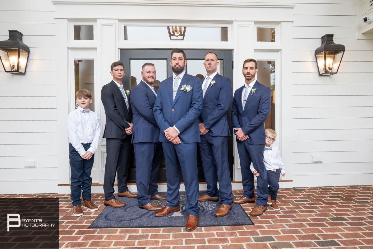 Groomsmen in navy suits sitting on white church steps.