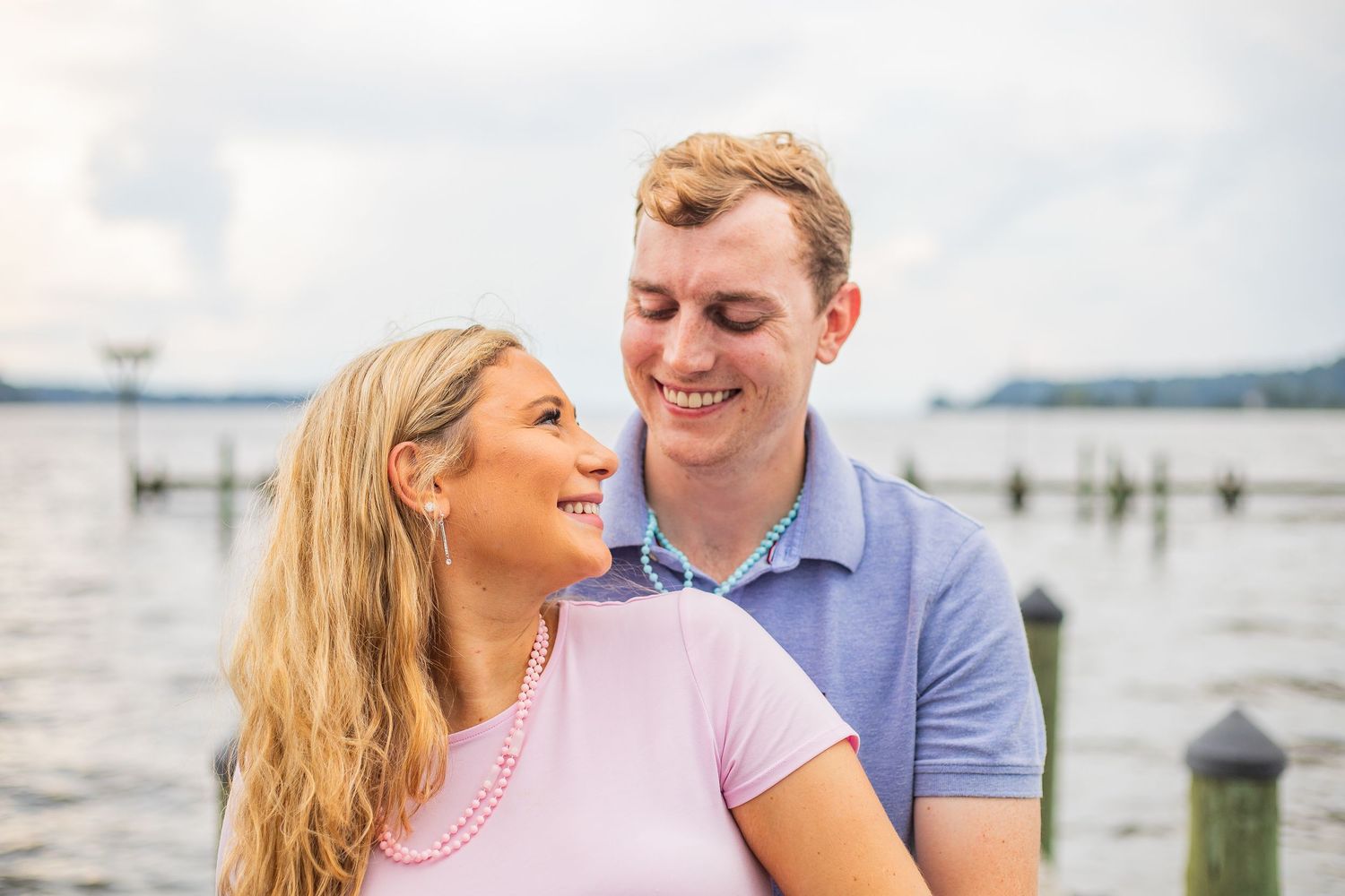 A couple sharing a romantic moment by the waterfront on a sunny day.