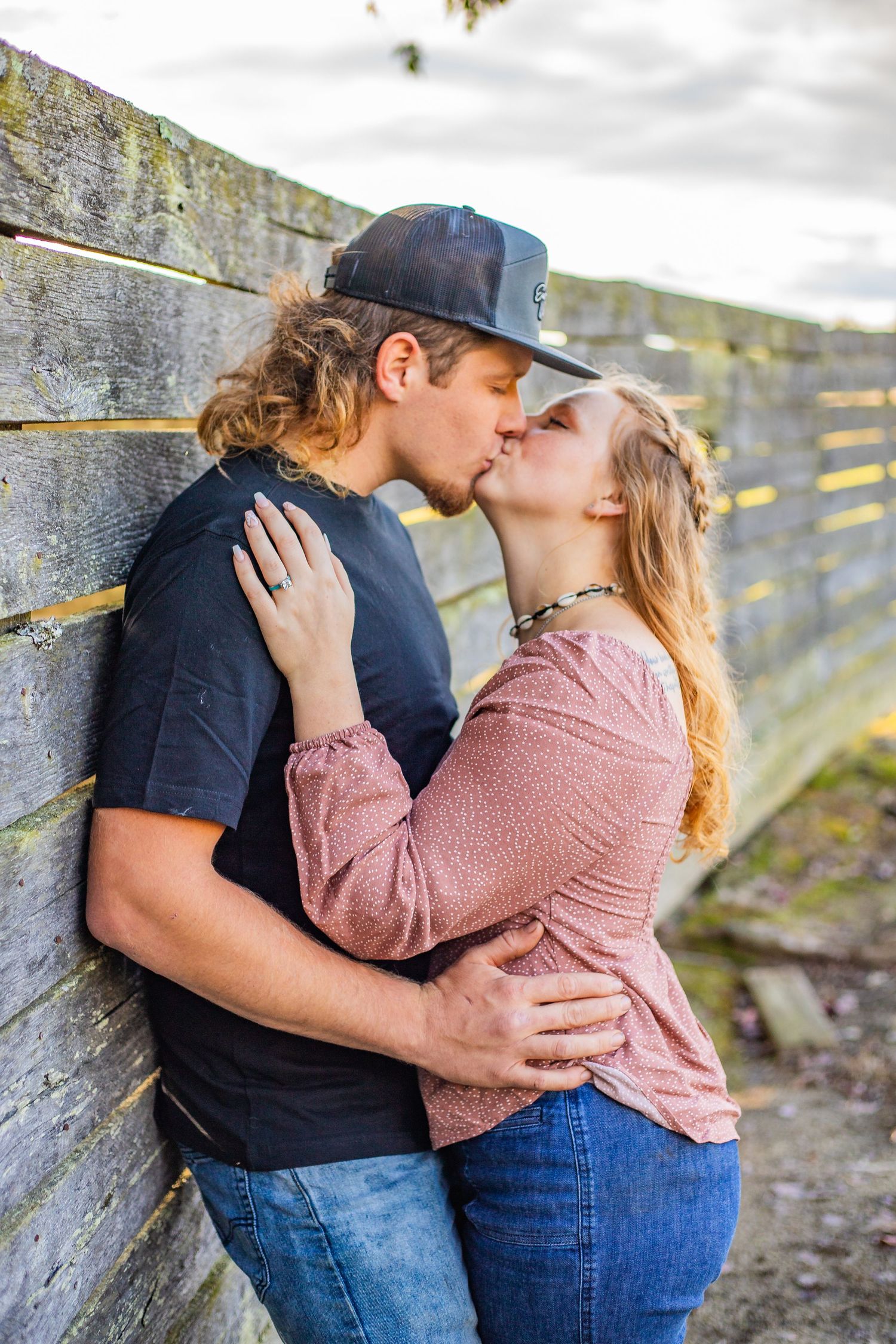 Couple sharing intimate moment against rustic stone wall backdrop.