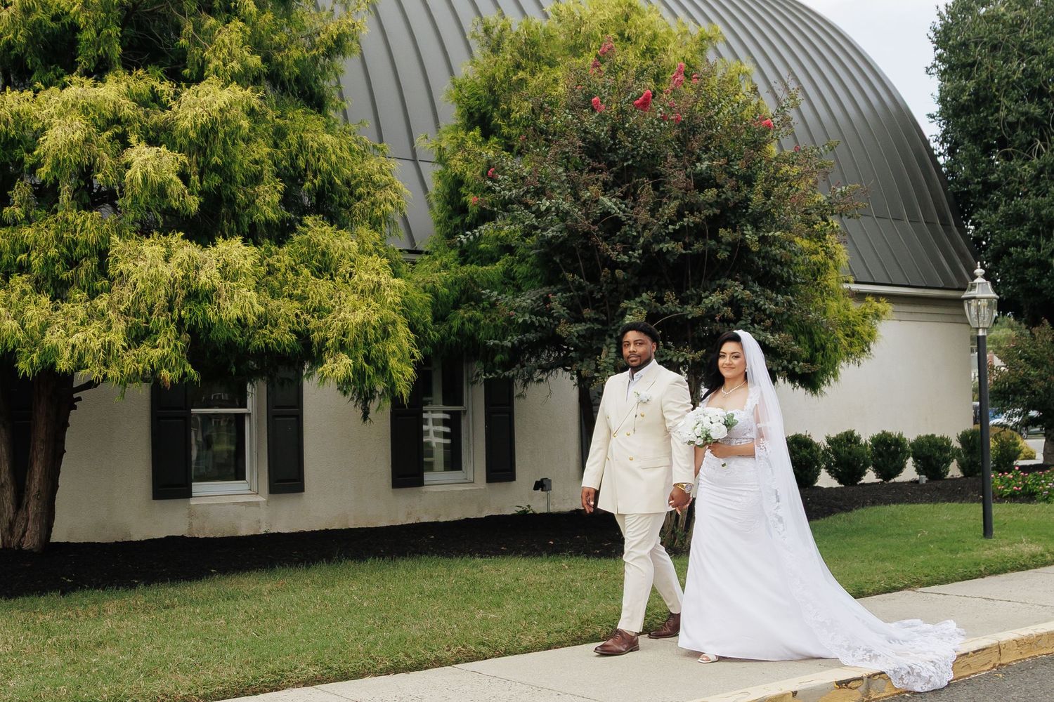 Wedding ceremony setup outside a building with curved architecture and landscaped grounds.
