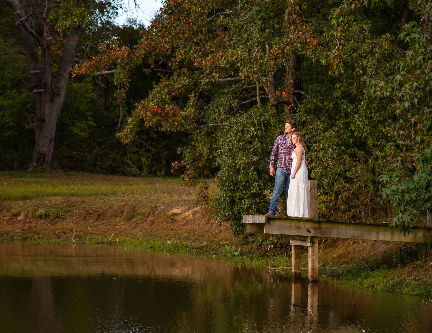 Tranquil pond surrounded by autumn trees with couple in distance.