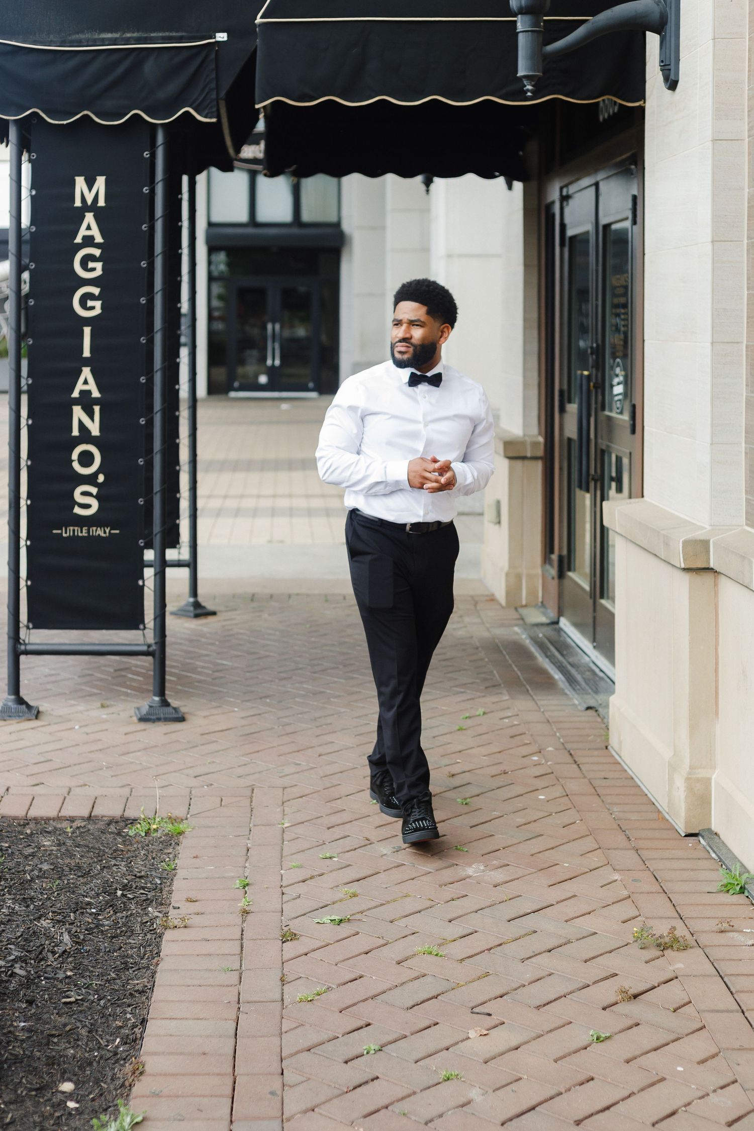 Formal attire portrait session outside a storefront with black awnings and signage.