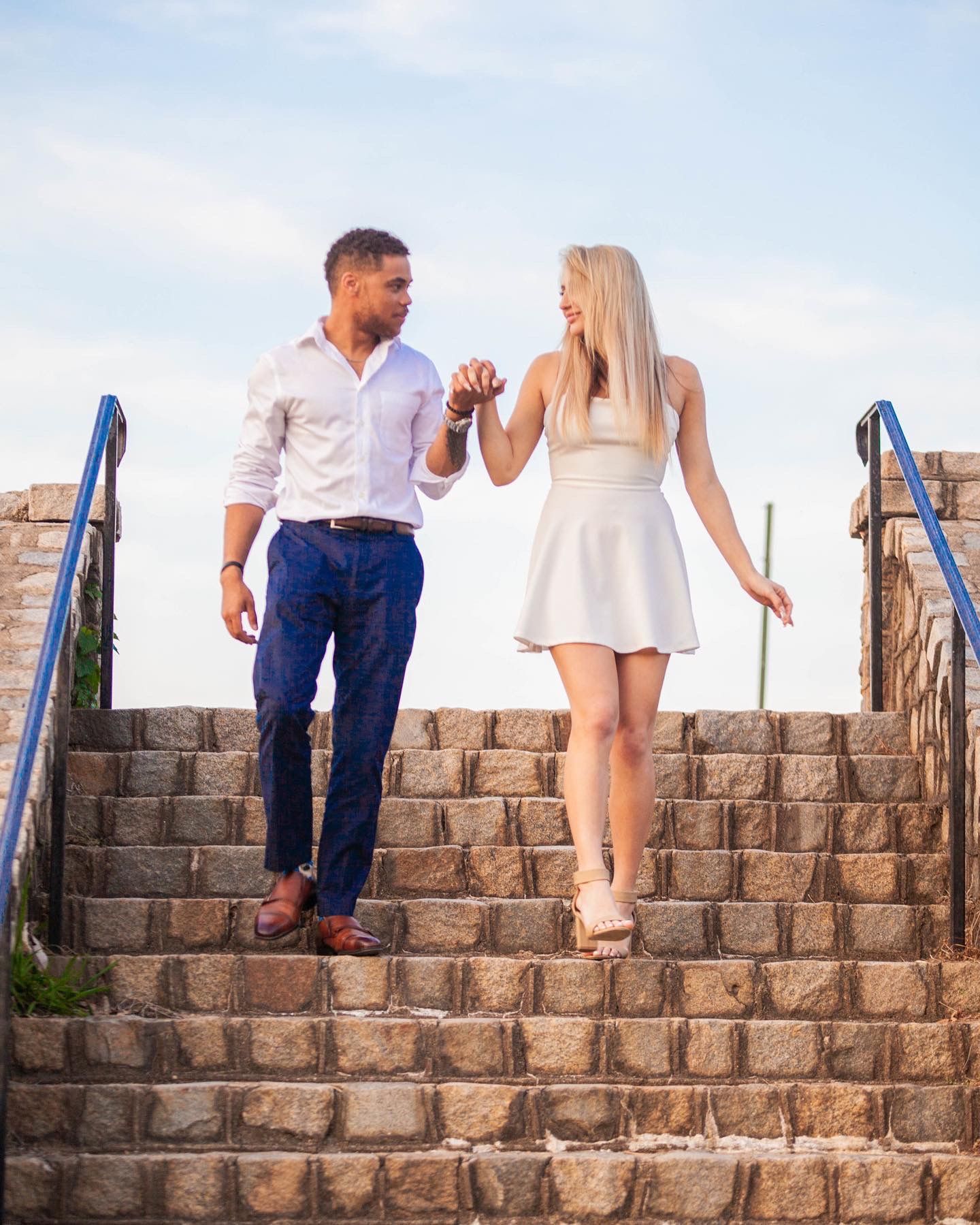 Couple descending stone steps together in coordinated white and blue outfits.