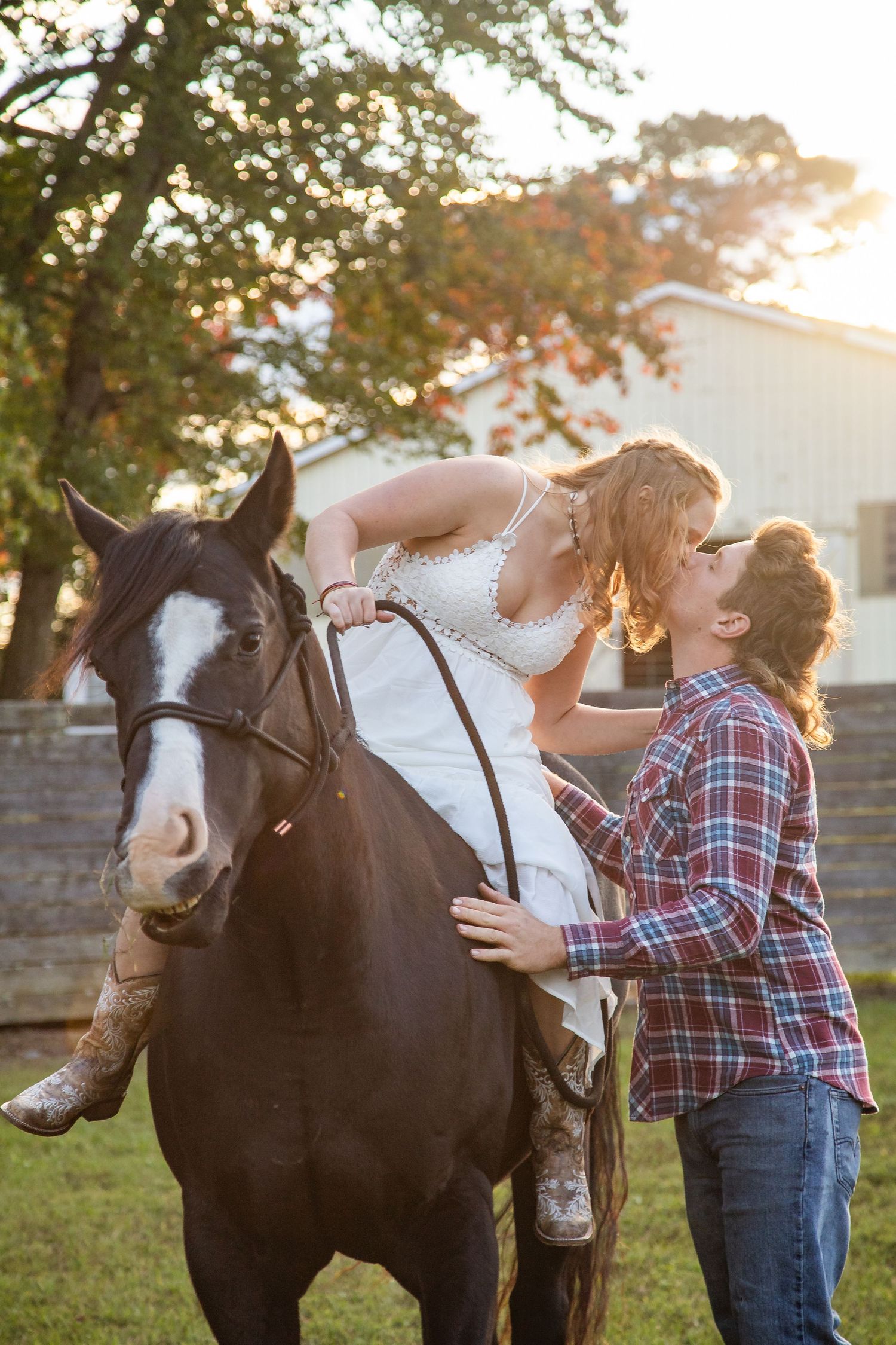 A young child in plaid interacting with a black and white horse in a sunny field.