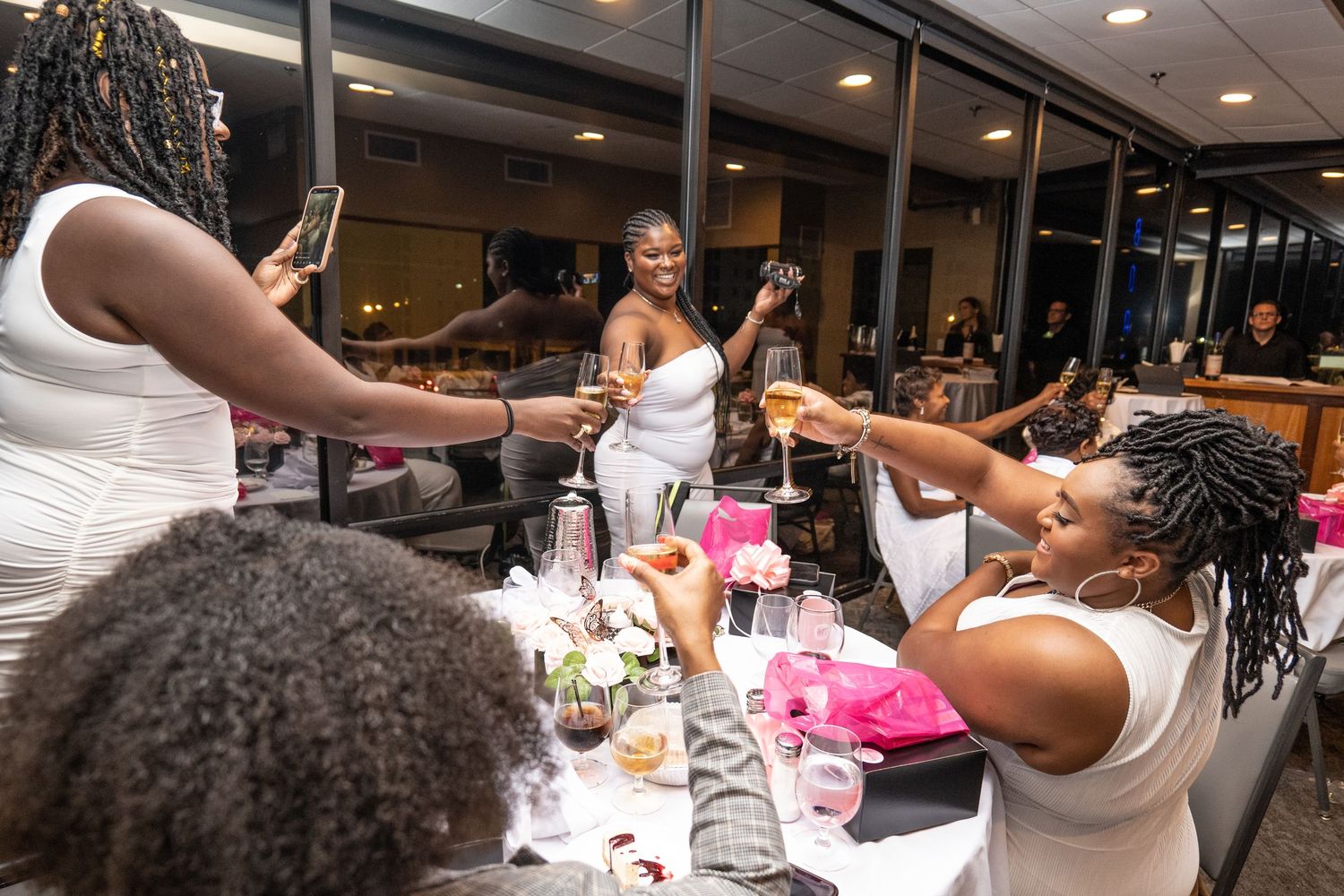Women in white dresses toasting with champagne glasses at an elegant party celebration event.