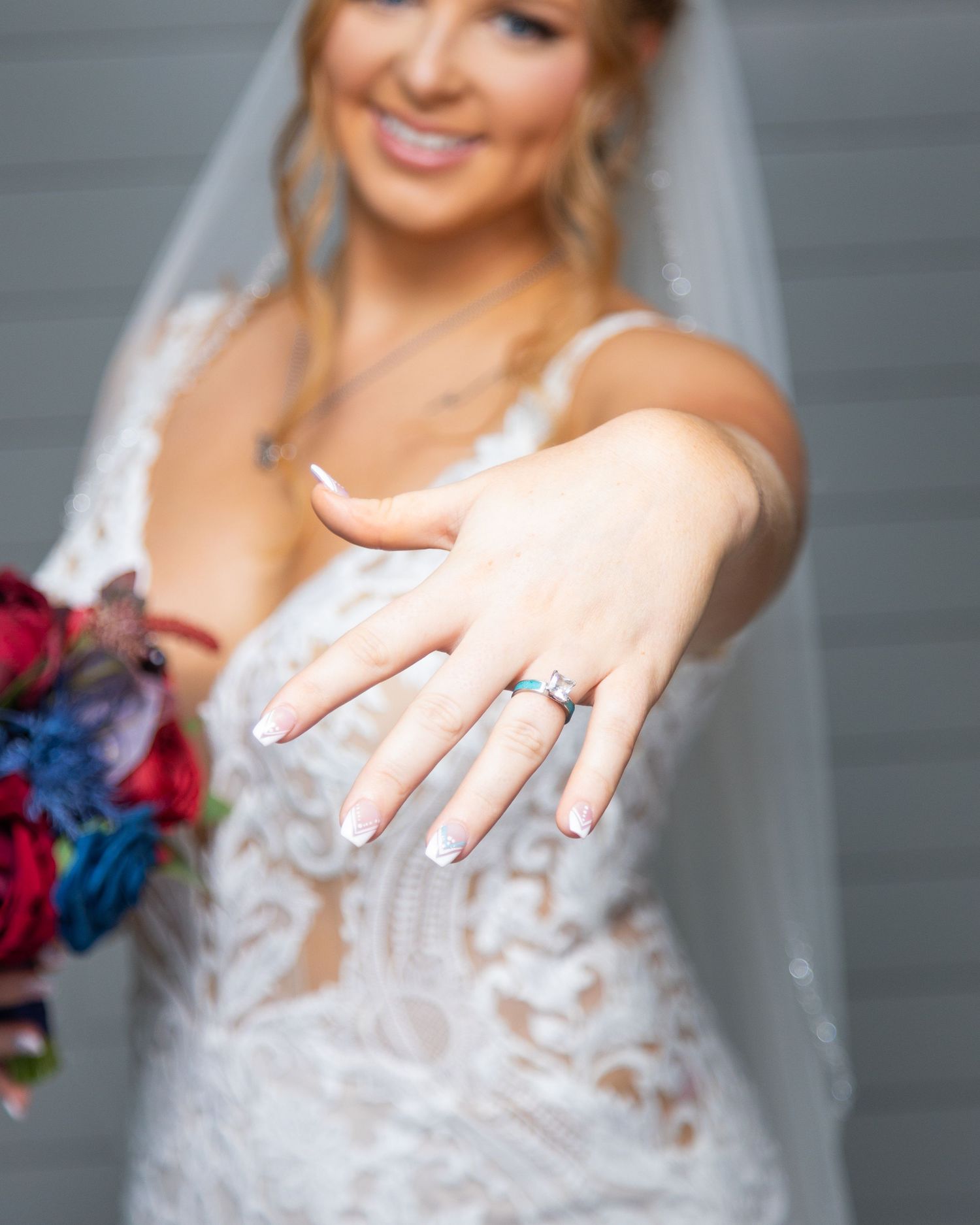 Close-up shots of a bride in a lace wedding dress showing off her engagement ring and wedding band.