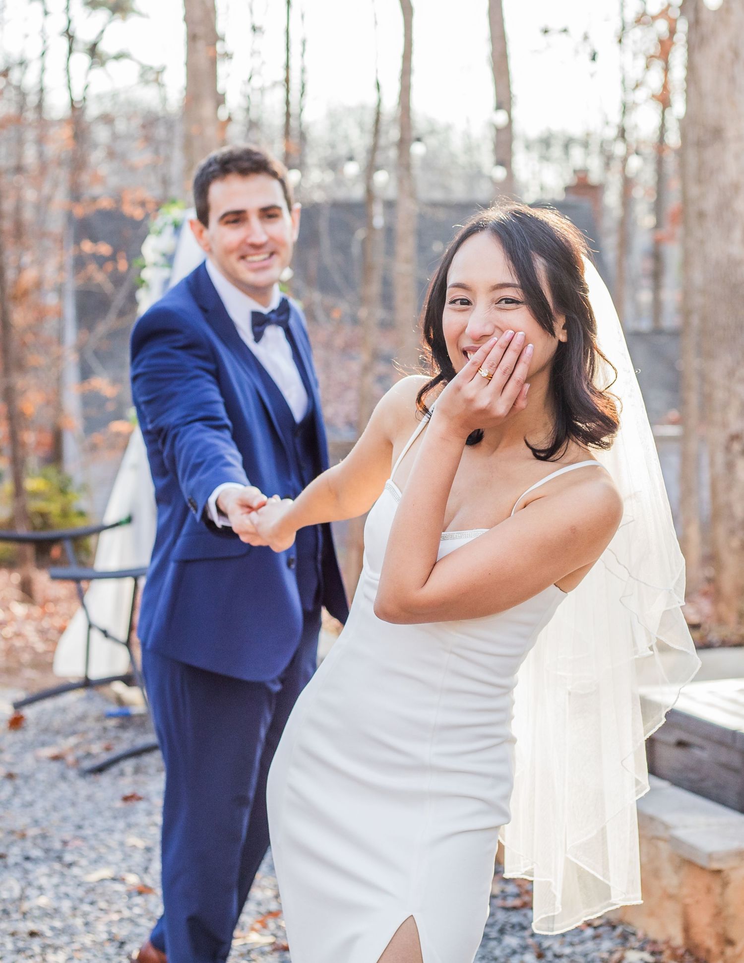 A joyful wedding moment captured outdoors with autumn foliage in the background.
