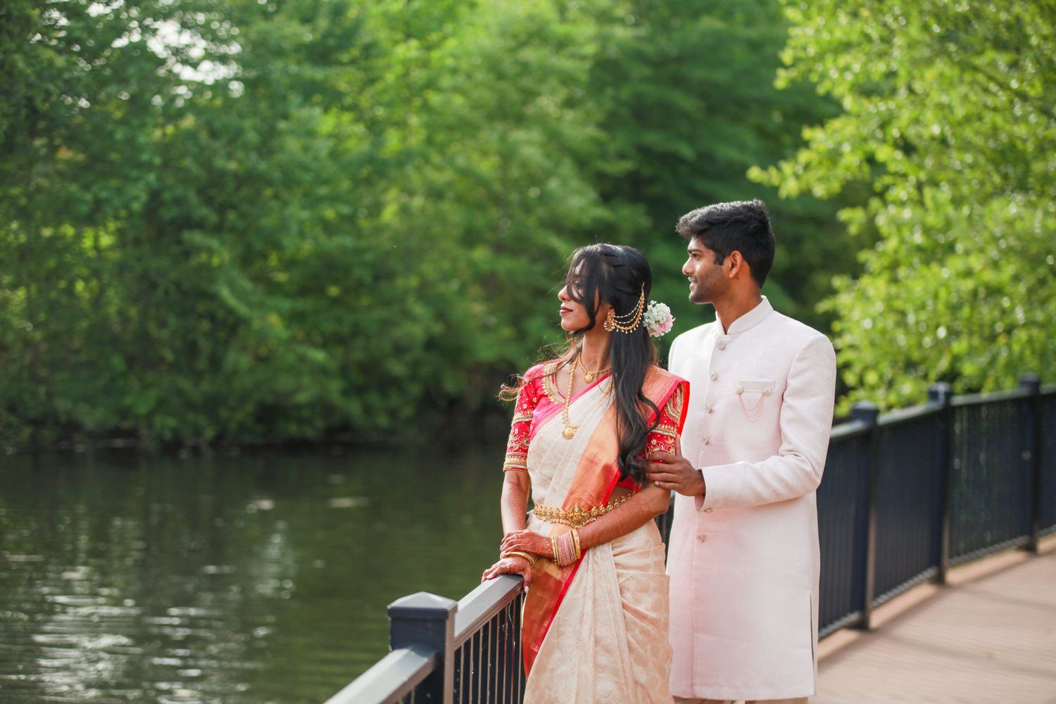 A romantic moment captured on a wooden bridge overlooking a serene lake with verdant surroundings.