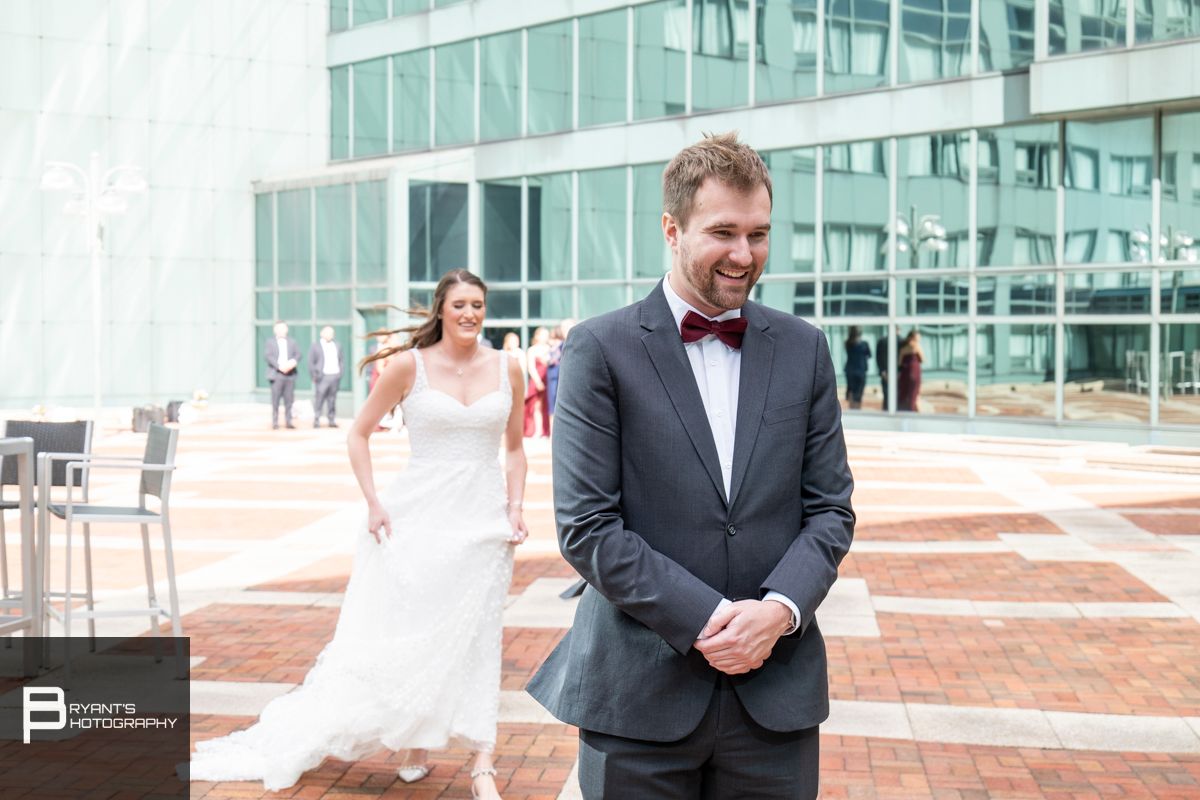 Wedding couple posing on urban rooftop with modern architecture in background.