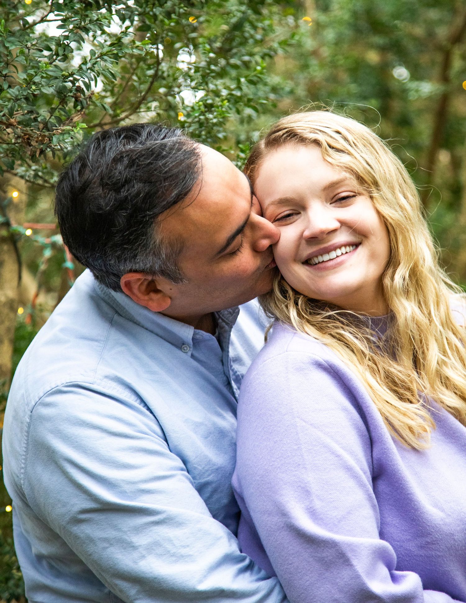 A couple sharing an intimate moment outdoors surrounded by greenery.
