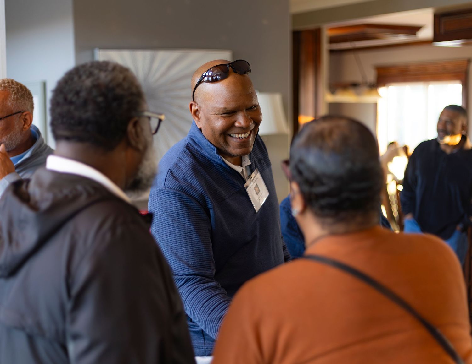 Group of men smiling and networking at an indoor social gathering event.
