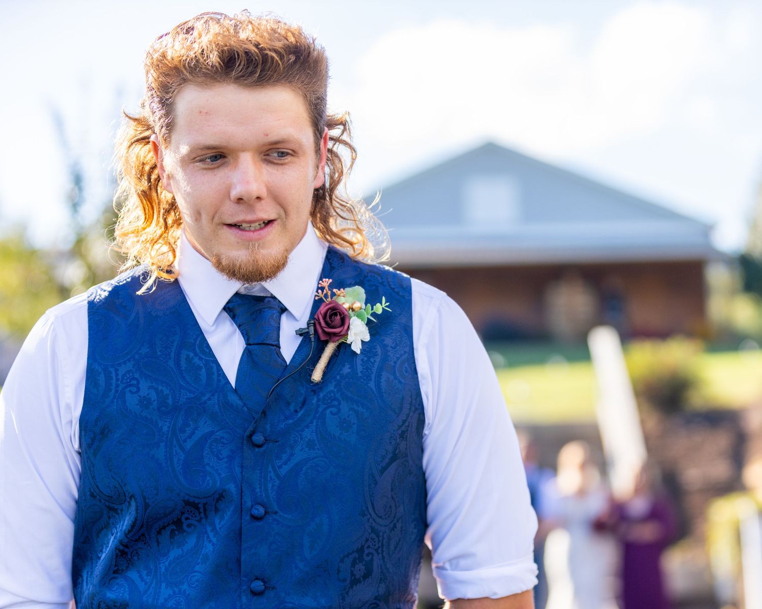 Wedding party members in navy blue vests and white shirts standing outdoors.