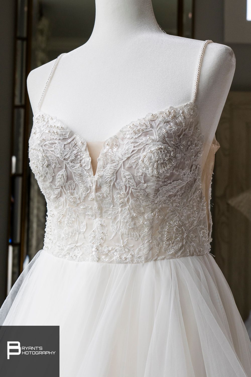 Close-up details of white wedding dress bodice with intricate lace embellishments.
