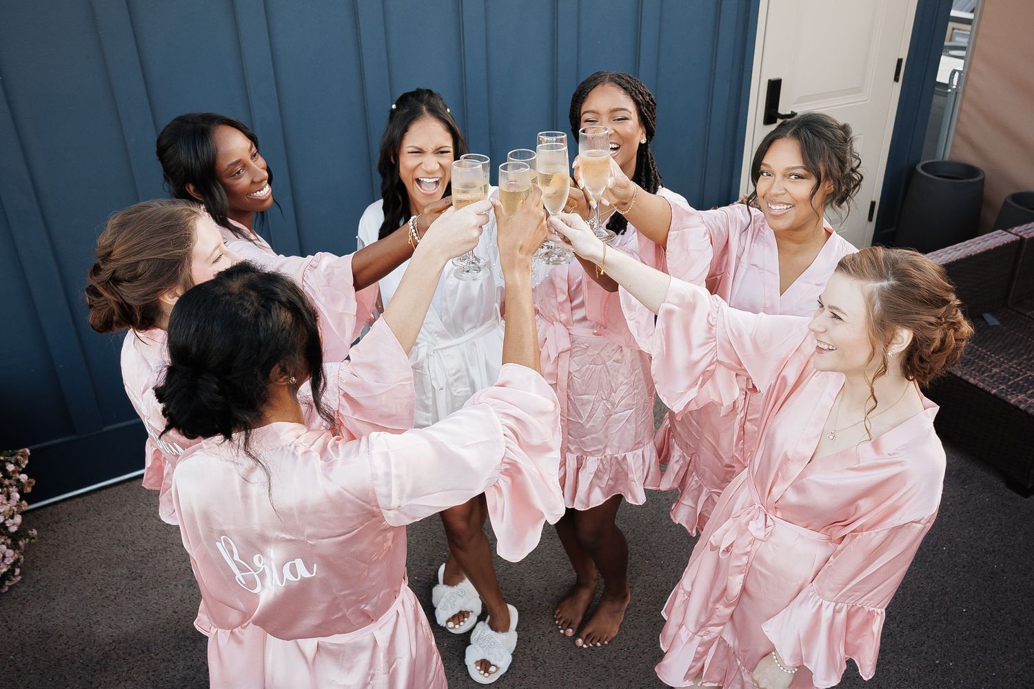 Bridesmaids in pink robes toasting with champagne glasses during pre-wedding celebrations.