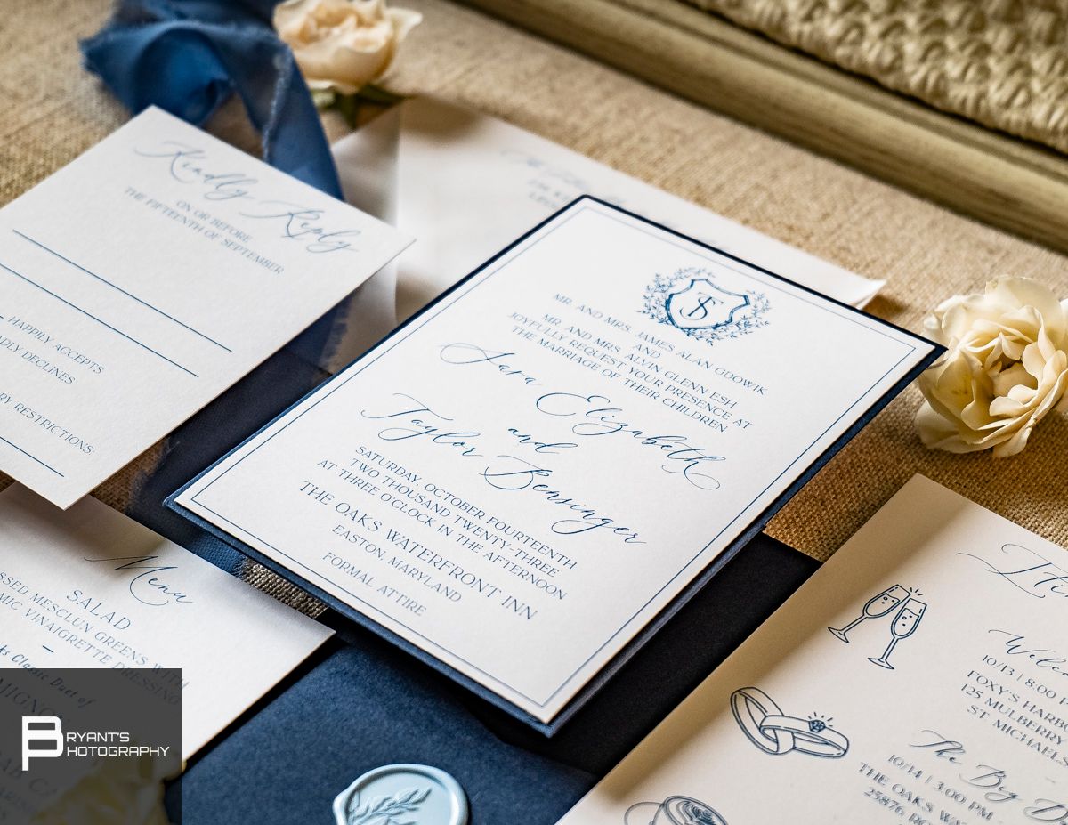 Elegant navy blue and white wedding invitation suite with wax seal and ribbon details.