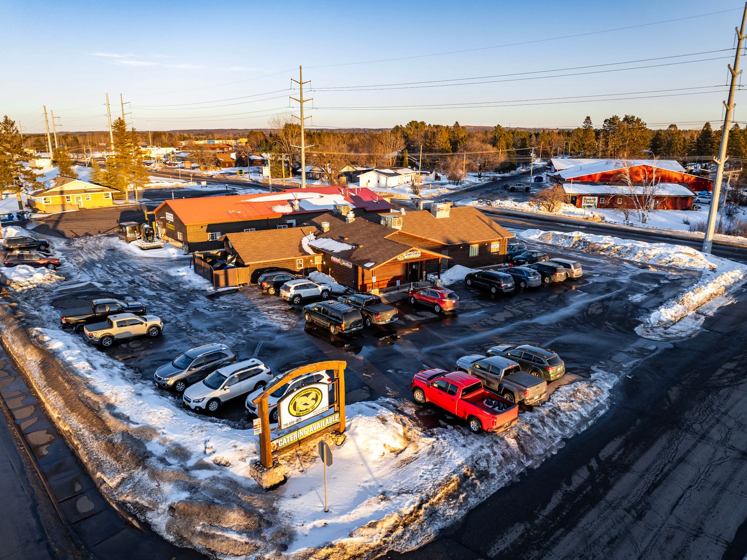 Panoramic winter view of a snow-covered parking lot filled with cars at an event venue.