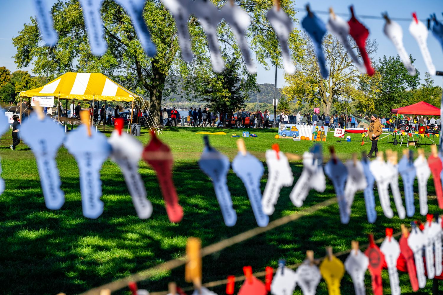 Prayer flags and banners strung between trees at outdoor festival setting.