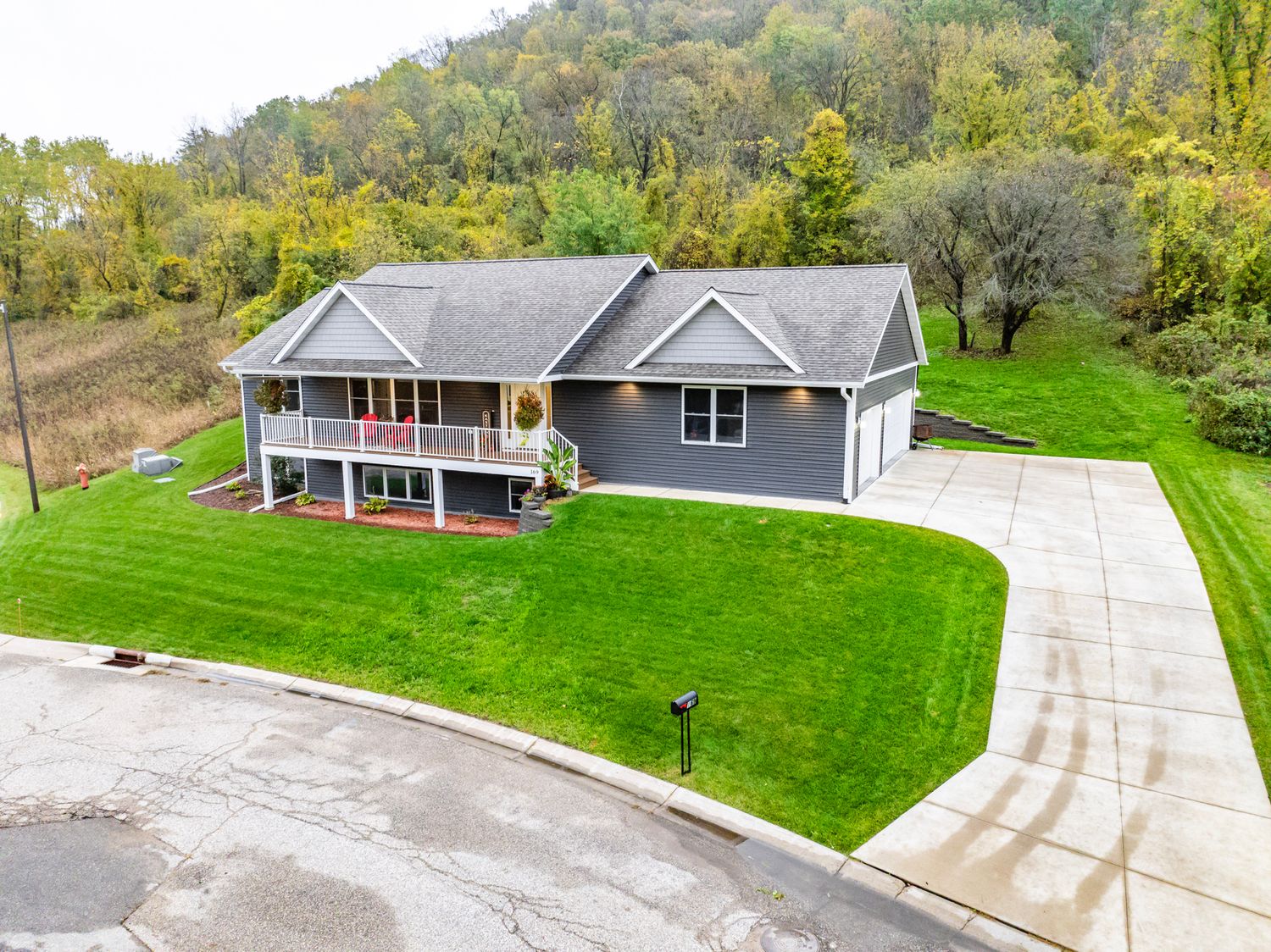 Aerial view of a residential property with green lawns and paved driveway.