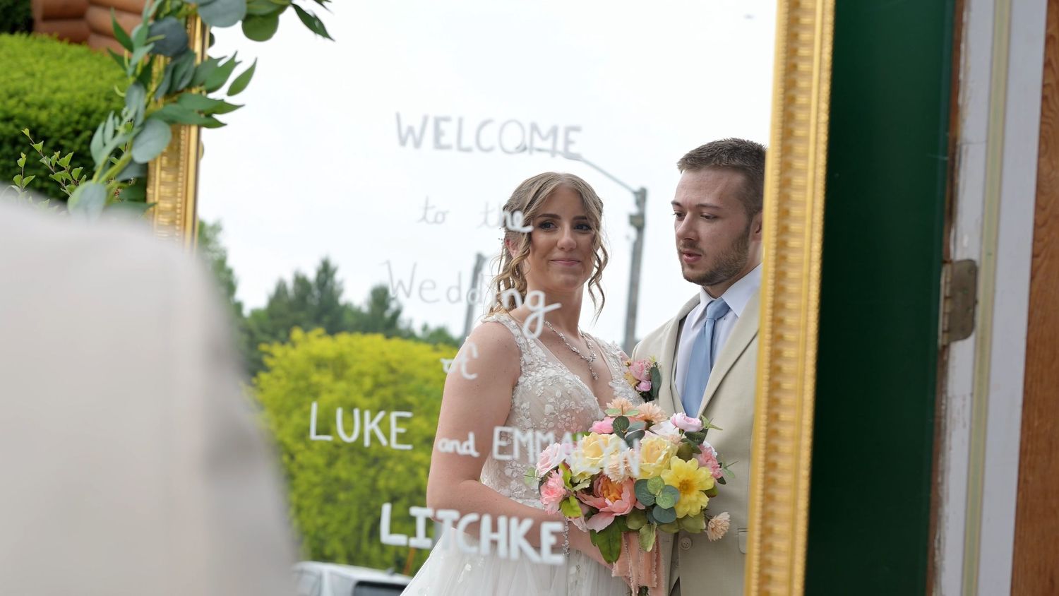 Elegant wedding welcome sign with floral decorations and gold frame.