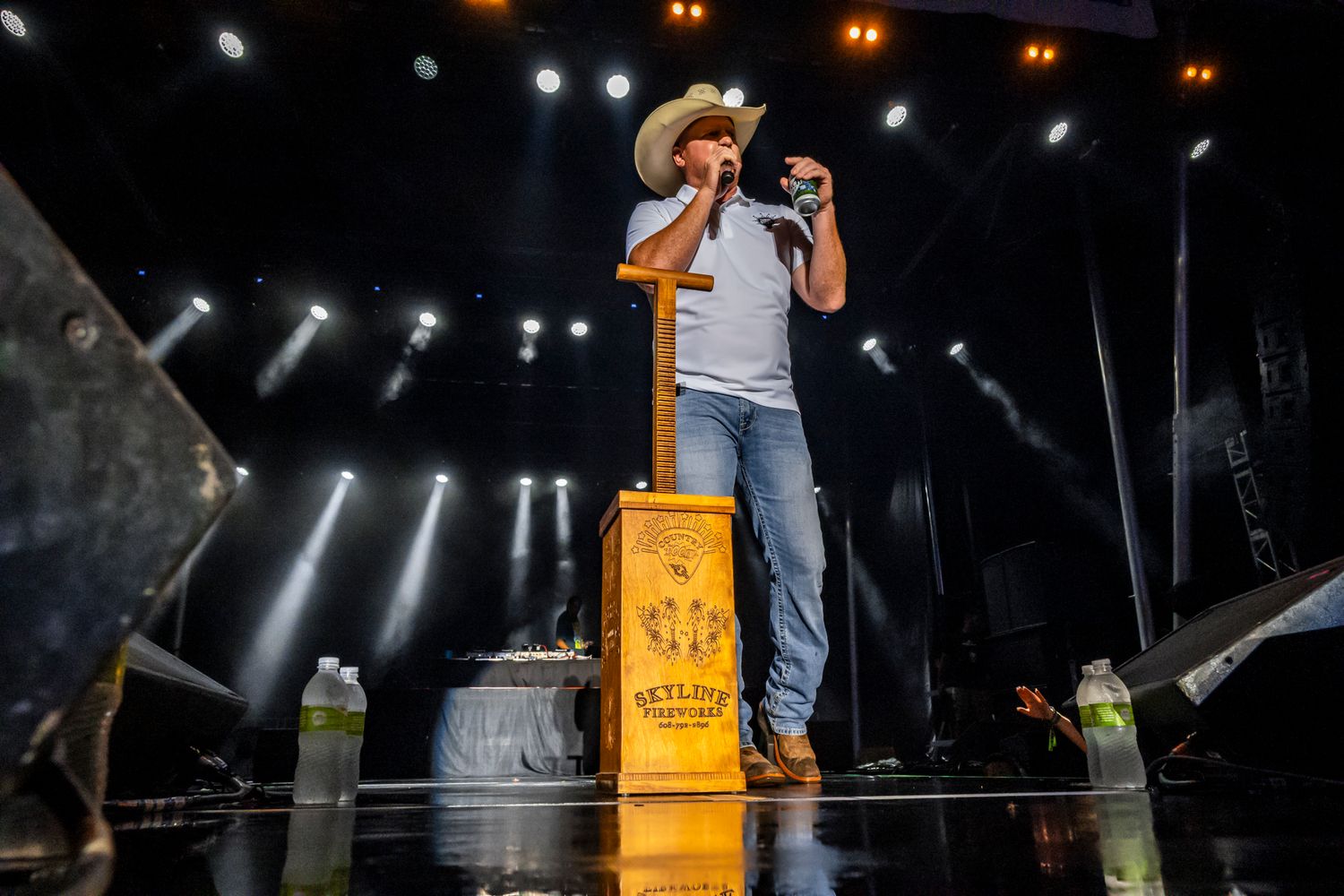 Country music performer singing on illuminated stage during nighttime concert performance.