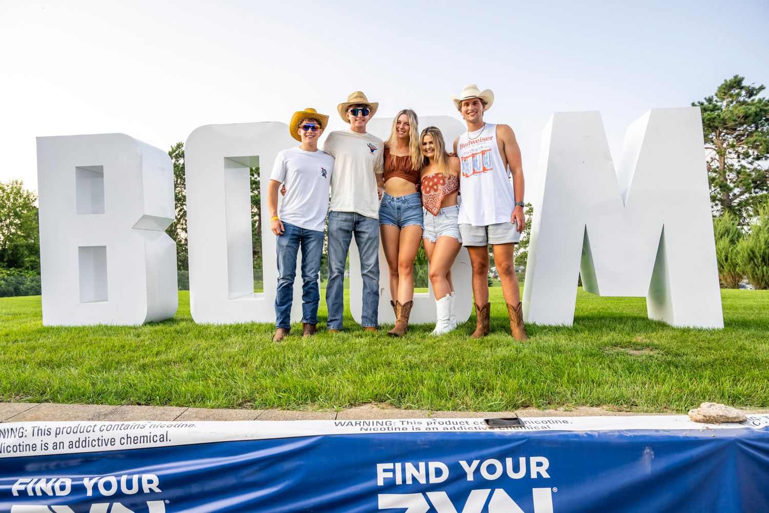 Group photo in front of large white EDM letters at an outdoor event.