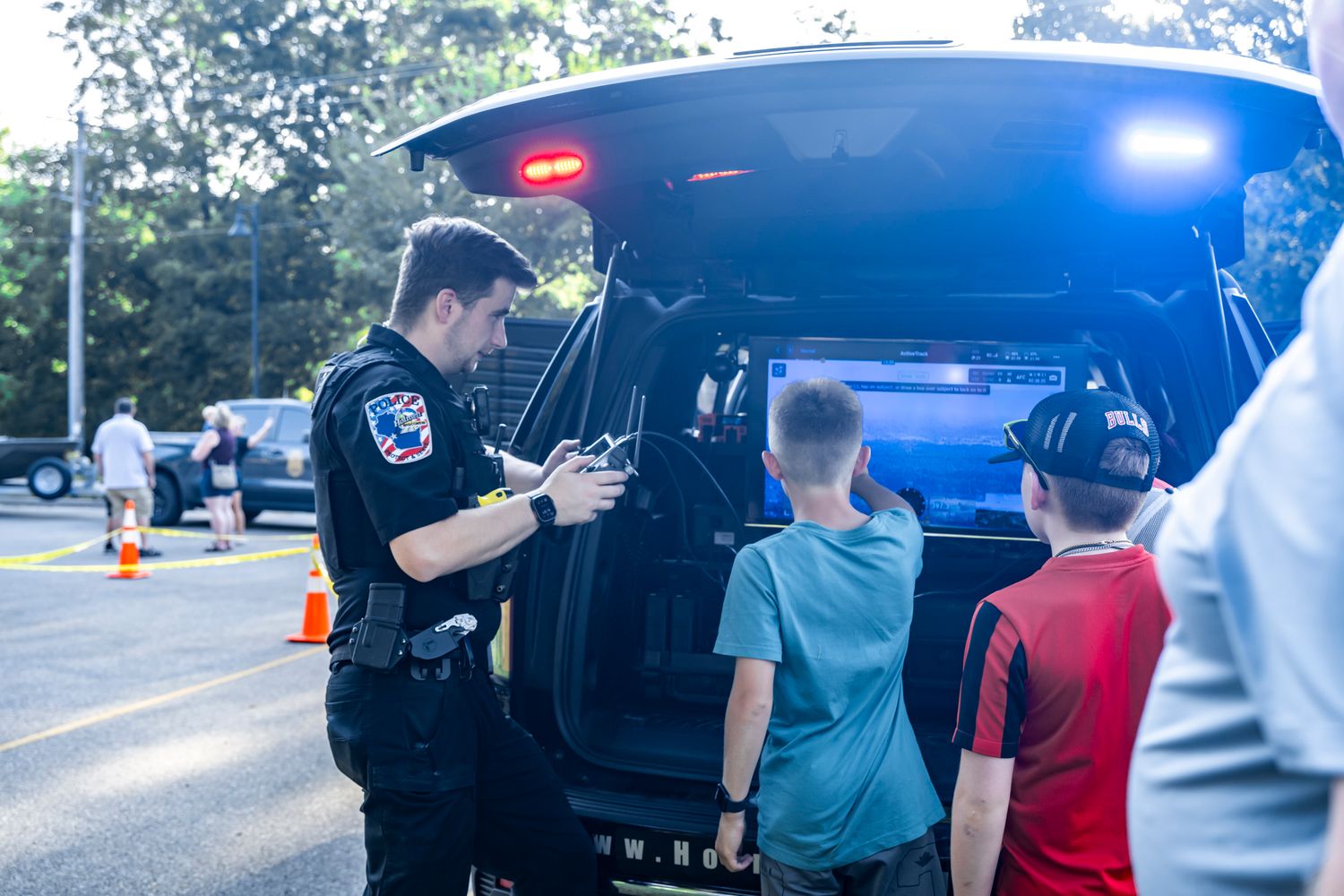 Police vehicle with emergency lights on display at a community event.